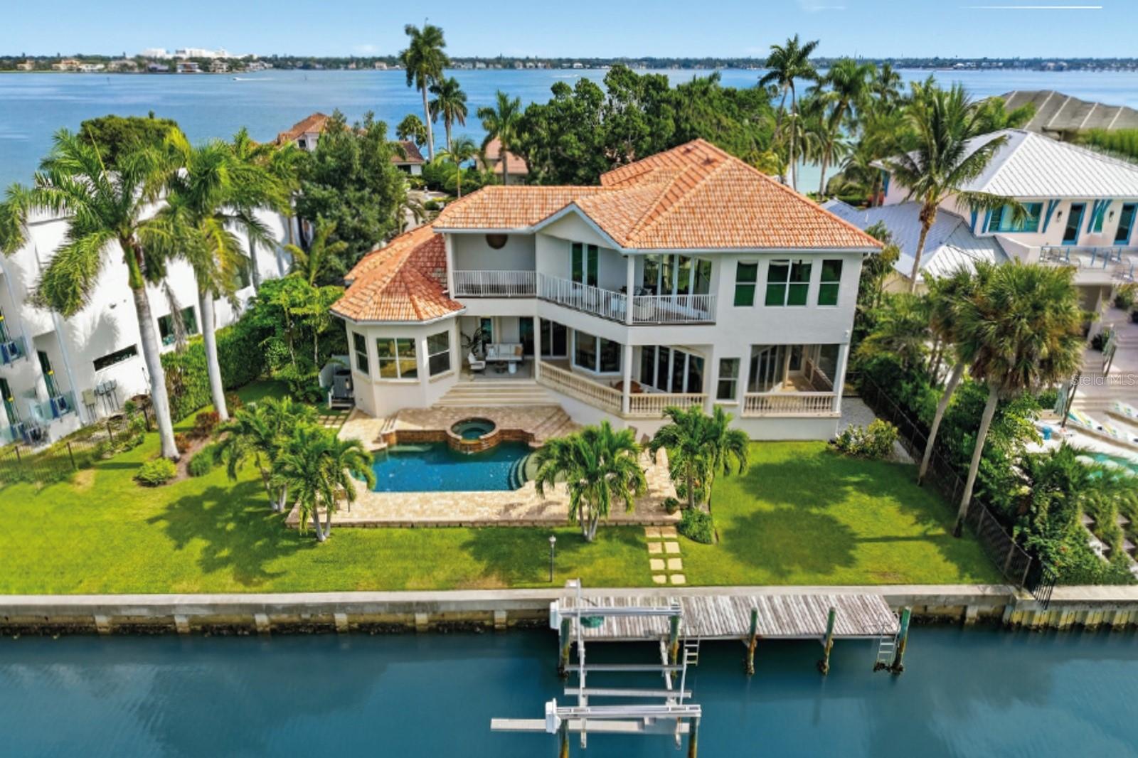 Custom-built elevated home by Voigt Brothers, completed in 2006 was purposefully designed to maximize the water views, this property feels far more distinctive than the typical canal-front home. Sunlight fills the interiors through numerous impact-rated windows, while ceilings rise to 11 feet, reaching nearly 13 feet in select areas to enhance the sense of space. The open-concept layout flows between well-defined living spaces, creating a balance of comfort and sophistication. The kitchen, integrates seamlessly with the family room and informal dining area, making it ideal for relaxed living and entertaining. A formal living room with a gas fireplace and a separate dining room add refinement, while the office provides privacy and flexibility. The primary suite on the main level features serene water views, direct terrace access, and ample space for a sitting area, along with a generously sized bathroom and walk-in closet. Also on the first floor, a guest area includes its own sitting area, bath, and private terrace, perfect for in-laws, extended family, or use as an additional office or gym. Upstairs, an oversized media room with a bar opens to a west-facing terrace showcasing sweeping water views. Three additional guest bedrooms and two bathrooms complete the upper level. Additional highlights include a three-car garage, spacious laundry room, two walk-in pantries and convenient pool bath. Outdoors, Sarasota’s signature indoor-outdoor lifestyle comes to life. The pool with spillover spa is surrounded by lush landscaping, four water-facing terraces, and inviting spaces for lounging or entertaining. The property offers an impressive 130 feet of water frontage, an 10,000 lb boat lift, and a dock. Bird Key is located just minutes from Lido Beach, St. Armands Circle, and downtown Sarasota, offering an exceptional combination of privacy, accessibility, and waterfront luxury. The Bird Key Yacht Club is also undergoing a complete rebuild, set to reopen in 2026 as one of Sarasota’s premier destinations for boating, dining, tennis, and social events.