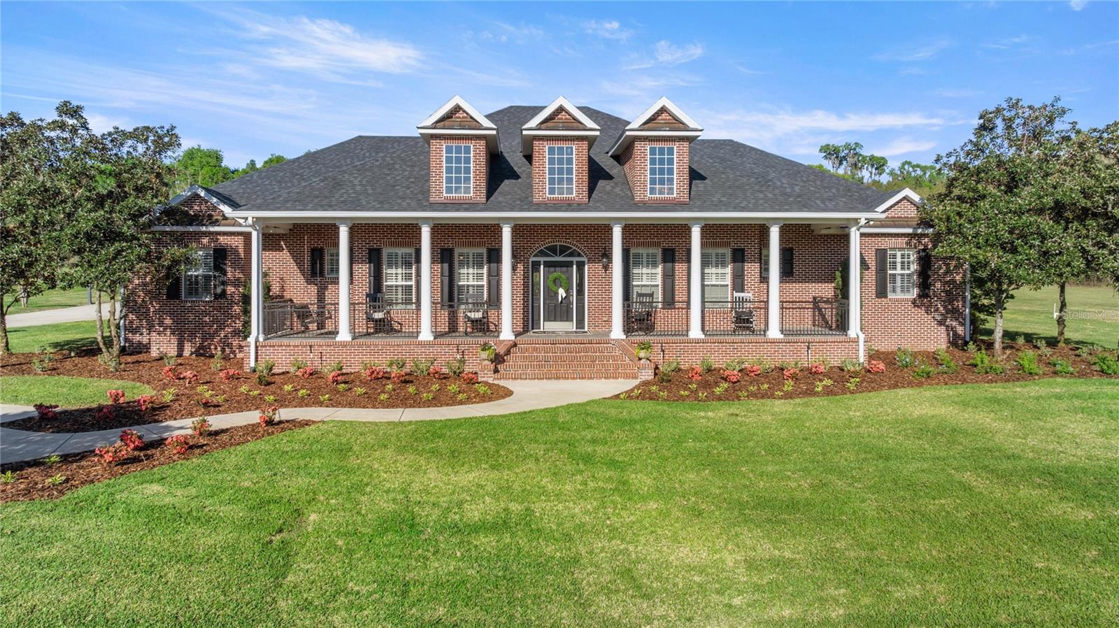 Located in the private gated community of Whisper Crest in SW Ocala, this all-brick estate home sits on a cleared 4.43 acres. The exterior boasts stately front porch columns, brick paver porches, and all-new professional landscaping. Extensive updates include a new roof, full interior refresh, exterior pressure washing, and much more—making this property truly move-in ready! Spanning a generous 4,158 square feet, the interior is masterfully designed for both comfort and privacy. All four of the spacious bedrooms function as private suites, each boasting full en-suite bathrooms and walk-in closets. The primary suite is oversized with elegant tray ceilings, dual walk-in closets with custom built-in shelving, and a spa-inspired bath complete with dual vanities, a soaking tub and a custom-tiled shower. A conveniently located half-bathroom easily accommodates guests. Continuing with the highly functional layout, the home features a living room, formal dining room, large secondary den, game/media room, and an indoor laundry room, with wood flooring running throughout the main areas. The spacious living room is anchored by a coffered ceiling and a classic brick gas fireplace, while the den offers vaulted wood-beam ceilings and a stone gas fireplace. The kitchen is equipped with granite countertops, professional-grade stainless steel appliances (including a gas stove), a large central island, and a distinctive brick accent wall. Adjoining the kitchen is a sun-drenched breakfast nook with expansive bay windows, alongside the formal dining room detailed with elegant wainscoting. Outdoor living is centered around a swimming pool and raised spa, upgraded with all-new pool equipment in 2026. The space is built for entertaining, featuring an oversized covered lanai with a full outdoor kitchen and a new grill, plus a separate poolside cabana with a built-in bar and a convenient half-bathroom. A stone fire pit sits nearby. Vehicle enthusiasts will appreciate the three-car attached garage with built-in storage, alongside a 900-square-foot detached garage featuring two large roll-up doors to easily accommodate boats or RVs. Additional property features include City of Ocala Fiber Internet, new water heaters, and two propane tanks that service the gas stove, both indoor fireplaces, and the hot tub. The large 4.43-acre lot and A3 zoning allow for up to one horse for each acre and provide ample space to build barns or equestrian facilities. The property is ideally situated for equestrian enthusiasts, located just 4 miles from the Florida Horse Park and 15 miles from the World Equestrian Center.