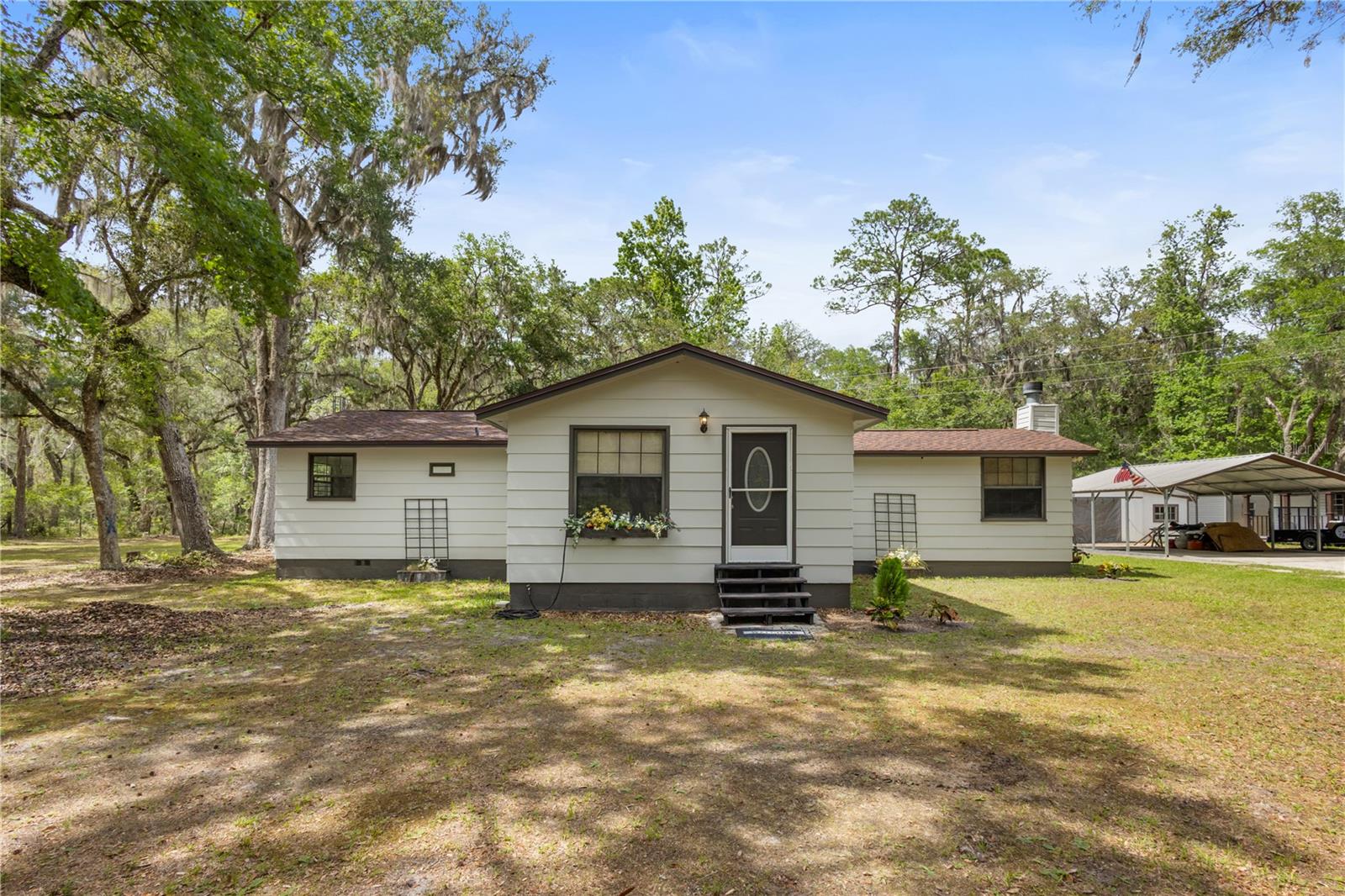 Set against a peaceful, wooded backdrop, this property offers privacy, space, and a functional layout with extensive updates already completed. The backyard borders the Newnans Lake Conservation Area, creating a quiet setting with no rear neighbors, while still being approximately 20 minutes from Gainesville.

Recent updates completed in 2025 include a new roof, hot water heater, and carpet, with the kitchen and bathrooms remodeled in 2021. The home sits on 3.02 acres and features full perimeter fencing with an automatic gated driveway.

Entering through the screened-in back porch, you step into a spacious great room with the kitchen just to the right. The kitchen opens to the living area, creating an easy, comfortable layout. Off the kitchen is the first bedroom and a full bath, while a separate hallway provides access to the primary bedroom, an additional bedroom, and the second full bathroom.

Outside features include a large carport, barn/workshop, and three storage sheds, and an exterior laundry area. Outdoor activities such as hiking, biking, fishing, canoeing, horseback riding, and wildlife viewing are available nearby, with a public boat ramp located approximately 2.5 miles away at Owens-Illinois Park, making this a well-rounded property that offers both convenience and a connection to nature.