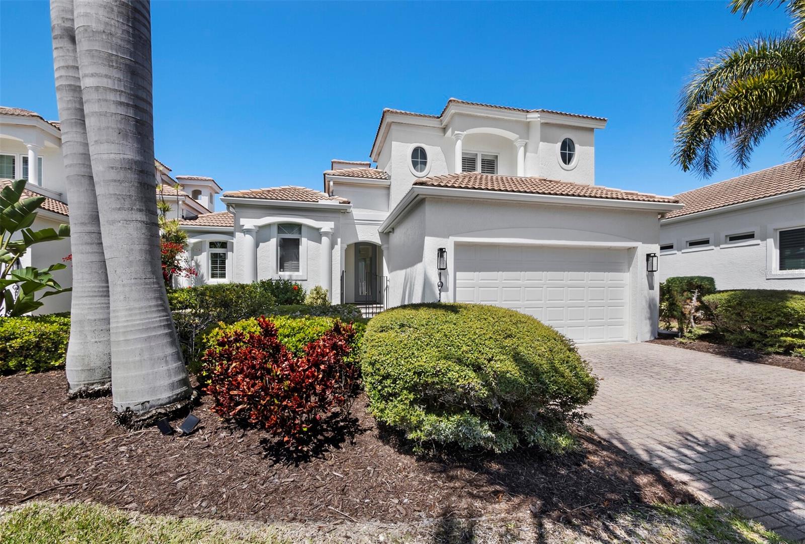 Tucked behind the gates of Bay Isles in the Emerald Pointe community, this 3BR/3.5BA residence offers 2,180+/- sq. ft. of thoughtfully designed living space with a layout that blends privacy, flexibility and inviting outdoor living. From the moment you arrive, a paver drive framed by lush landscaping and a striking 2-story façade with barrel tile roof set a warm and welcoming tone. A paver walkway leads to the courtyard entrance that defines the home’s character. This open yet private space is bathed in natural light and features a covered and screened sitting area with an all-season kitchen, creating a unique setting for entertaining or quiet relaxation. Just off the courtyard, a separate casita with its own full bath offers ideal space for a home office, guest suite or creative retreat. Inside, the home feels open and spacious, with large tile flooring, high ceilings and a thoughtful mix of clerestory and transom windows that bring light into every corner. Neutral tones and layered textures add depth without distraction. The living room is both functional and inviting, featuring a fireplace, built-in wine refrigerator, and ice maker that enhance the space for everyday living or hosting. The kitchen has been beautifully updated and connects naturally to the main living areas. It features stone countertops, all-white cabinetry, stainless steel appliances, a tile backsplash and a breakfast bar, along with a dining area highlighted by a striking aquarium window that looks back into the courtyard. The primary suite is located on the main living level in a private wing, offering direct access to the pool and a generous walk-in closet. The bath is well appointed with dual vanities, a freestanding tub, a walk-in shower and refined tilework. Upstairs, a guest bedroom provides comfort and privacy, complete with wood flooring, a walk-in closet, desk space and an en suite bath. At the back of the home, a screened lanai and pool overlook a peaceful lake with fountain, where large-panel screening keeps the view open and unobstructed. Additional features include an in-residence laundry room and a two-car garage with abundant storage. Residents of Emerald Pointe enjoy a maintenance-free lifestyle along with access to the private Bay Isles Beach Club, offering white sand beaches just minutes away. Optional membership to the Longboat Key Club further enhances the lifestyle with championship golf, tennis and pickleball, a private beach club, marina, spa and wellness amenities, multiple dining venues, and an active social calendar.