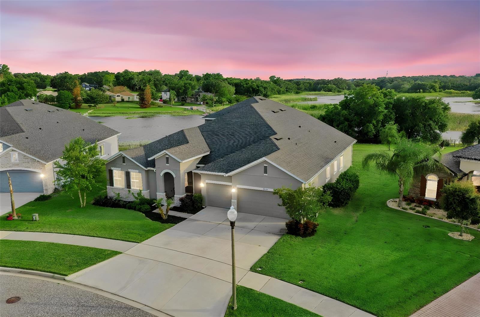 **Video Tour Available** Wake up to shimmering water views and step into the lakefront lifestyle you’ve been dreaming of. Set on 151 feet of direct frontage on Johns Lake, this exceptional home invites you to spend your days boating, paddleboarding, or simply soaking in the peaceful beauty right from your large backyard. Your private dock (4’ x 140’), boathouse (12’ x 36’), boat lift, and double jet ski lift mean the water is always just moments away—no packing, no planning, just effortless access to life on the lake.  Designed for both connection and comfort, the Boulevard floor plan by David Weekley offers a seamless flow with all bedrooms conveniently located on the main level. Whether you’re hosting guests or creating a private retreat for family, the layout provides the perfect balance of openness and quiet spaces. A front bedroom with its own bath offers ideal accommodations for visitors or multi-generational living, while a dedicated office with French doors and custom built-ins creates an inspiring place to work or unwind.  At the heart of the home, the gourmet kitchen is made for gathering—featuring granite countertops, stainless steel appliances, a stylish tile backsplash, and a large island where conversations naturally unfold. The dining and family rooms are filled with natural light and frame stunning lake views, turning everyday moments into something special. From cozy evenings by the stone-accented fireplace to meals shared with the water as your backdrop, every space feels connected to the outdoors.  Enjoy the screened patio and embrace true indoor-outdoor living, where sunsets over the lake become part of your nightly routine. The primary suite is a private haven, offering breathtaking water views, a generous walk-in closet, and a spa-like bath with dual vanities, a frameless shower, and a relaxing garden tub.  The 3rd and 4th bedrooms share a 2nd living room and full bathroom.  Upstairs, a versatile bonus room with a wet bar and full bath opens to a screened balcony overlooking the lake—perfect for entertaining, game nights, or simply enjoying a quiet evening under the stars.
Thoughtful upgrades throughout—including ceiling fans, built-in features, a spacious laundry room, epoxy garage flooring with overhead storage, and convenient holiday lighting outlets at the roof line—enhance comfort, lifestyle and functionality.  This isn’t just a home—it’s your everyday escape, where lakefront living becomes your new normal.