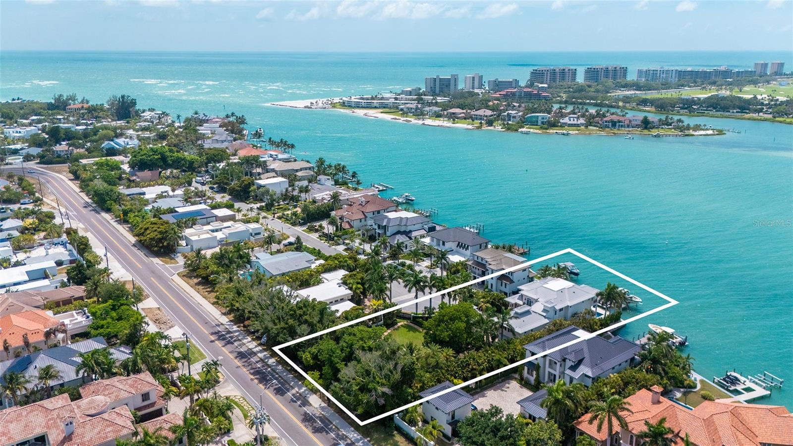 At the end of Westway Drive, where Lido Shores meets the open water of New Pass, 1435 Westway Drive occupies one of Sarasota’s most extraordinary waterfront settings. Private, gated, and set on a double lot, the estate captures sweeping views across New Pass toward Longboat Key while offering direct deepwater access to the Gulf of Mexico and Sarasota Bay.

This is the rare property that delivers every element of elevated coastal living in one address: boating, privacy, architectural presence, beach access, proximity to St. Armands Circle, and a level of land rarely found on Lido Key.

Designed by Brian Phipps and built in 2013, the British West Indies–inspired residence blends timeless coastal architecture with modern luxury. Inside, expansive living spaces are framed by tall ceilings, walls of glass, rich wood flooring, custom millwork, and a natural connection to the water beyond. The great room opens to the waterfront terraces, creating an effortless flow between interior comfort and outdoor living.

The kitchen is designed for both daily living and large-scale entertaining, with premium appliances including Sub-Zero and Wolf, generous stone surfaces, custom cabinetry, and an open connection to the main living and dining areas. Whether hosting guests after a day on the boat or enjoying a quiet evening overlooking the water, the home feels equally suited to celebration and retreat.

With five bedrooms, two primary suites, and elevator service, the floor plan offers rare flexibility for owners, family, and extended guests. The upper-level owner’s retreat is a private sanctuary, complete with a sitting area, wet bar, wine refrigeration, espresso station, study, dual walk-in closets, and a terrace overlooking New Pass, the Gulf, and the lights of Longboat Key beyond.

The outdoor living experience is exceptional. Covered terraces, a summer kitchen, resort-style pool, waterfall feature, and waterfront lounge spaces create a private setting designed around the view. The dock includes a 24,000-lb boat lift and additional jet ski lift, placing premier boating waters directly at your door. From here, New Pass provides immediate access to the Gulf, Sarasota Bay, Longboat Key, and the surrounding barrier islands.

What truly sets the property apart is its scale. The estate spans approximately three-quarters of an acre, including an adjacent parcel that has been transformed into a lush private garden with mature landscaping, open lawn, fire pit, pond, cascading waterfall, and meandering paths. It gives the home a sense of arrival and breathing room that is almost impossible to recreate in this location. With its own gated access and generous dimensions, this portion of the property also offers future flexibility for a guest house, wellness pavilion, additional structure, or further reimagining, subject to applicable approvals.

Lido Shores remains one of Sarasota’s most coveted coastal enclaves, known for its architectural pedigree, quiet streets, private beach access, and rare positioning between the Gulf, New Pass, St. Armands Circle, downtown Sarasota, and Longboat Key. Residents enjoy the privacy of a true neighborhood while remaining moments from dining, shopping, boating, beaches, and culture.

Previously recognized as an HGTV Ultimate House Hunt winner for waterside living, 1435 Westway Drive is more than a waterfront residence—it is a private Sarasota estate with presence, scale, and a setting that cannot be duplicated.