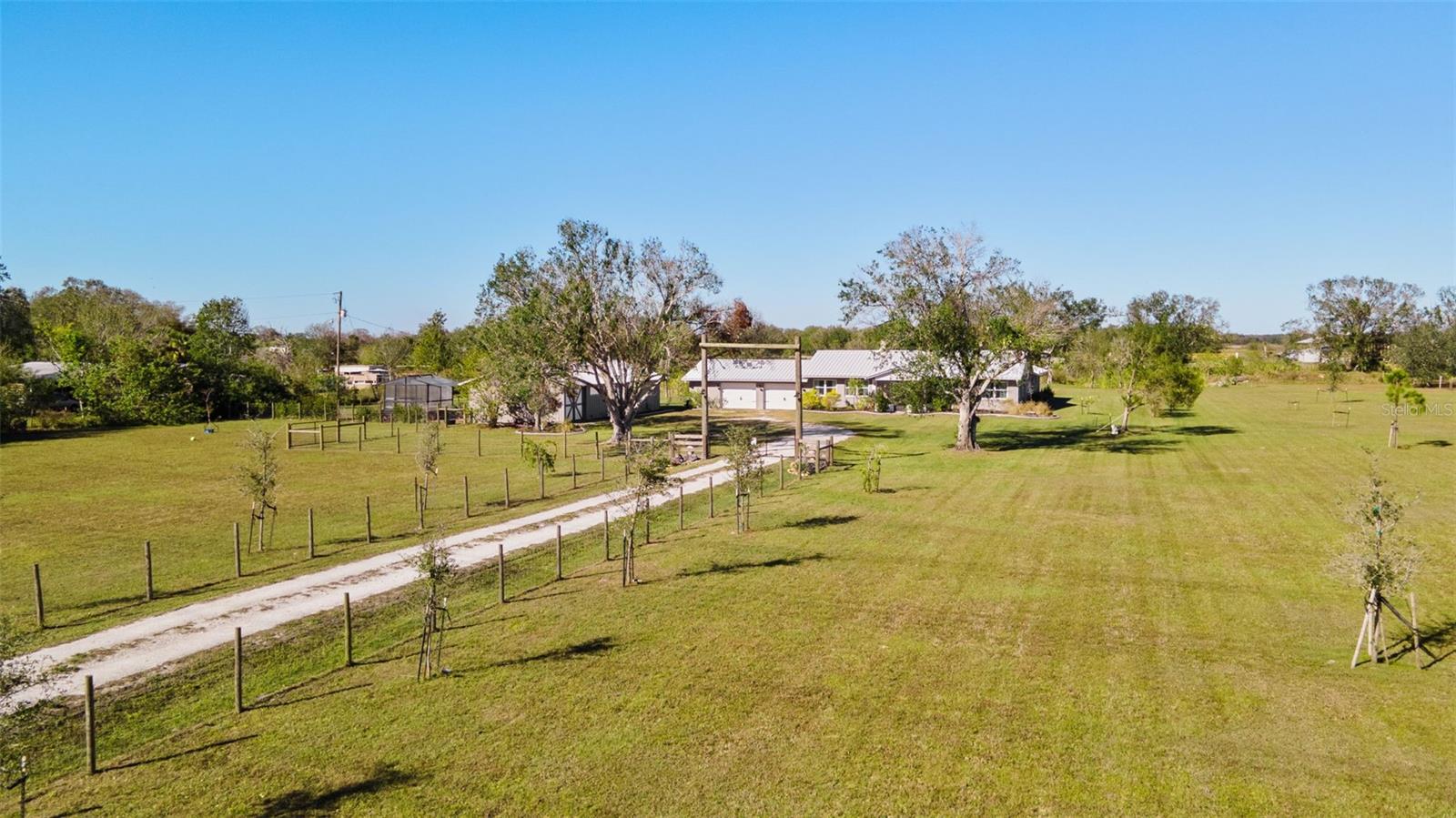 Enjoy country living at its finest on 5 beautiful fully fenced acres with a private POND!  Located securely behind your electronic gate, you approach this rambling ranch home which has been tastefully renovated to the highest standards.  Charmingly decorated in neutral tones, this 3 bedroom, 2 bath home has an incredible amount of space for your every rural need.  There is a huge 2 car garage plus a 24x50 workshop with concrete floors and electric – this structure has so many possibilities beyond storage, for example an art or ceramic studio, a woodworking shop, a home brewery – the possibilities are endless.  If you are an Equestrian at heart, there is also a horse stall available for your use.  Just some of the major updates include all new Impact windows and doors, a metal roof, luxury vinyl flooring throughout, custom wood kitchen cabinets with granite countertops, stainless steel appliances, a double oven convection range, a double farm sink with subway tile backsplash and a spacious breakfast room.  On chilly evenings you will truly enjoy the cozy warmth of the double sided wood burning stone FIREPLACE open to both the Great Room and Formal Dining Room.  The primary bedroom features sliders to a patio just steps from the outdoor firepit with curved seating and a  wood pergola with dual porch swings.  The all season Florida room will be one of your favorite places to relax at any time of the year.  This estate offers all the privacy you could wish for plus the convenience of just a short drive (less than 15 minutes) for your day to day shopping needs.  It is less than a 45 minute drive to quaint and historic Punta Gorda and Fisherman’s Village where you will find great shopping, restaurants from casual to gourmet, museums, art galleries, entertainment and marinas.  Come and live the sunny Florida lifestyle every day!