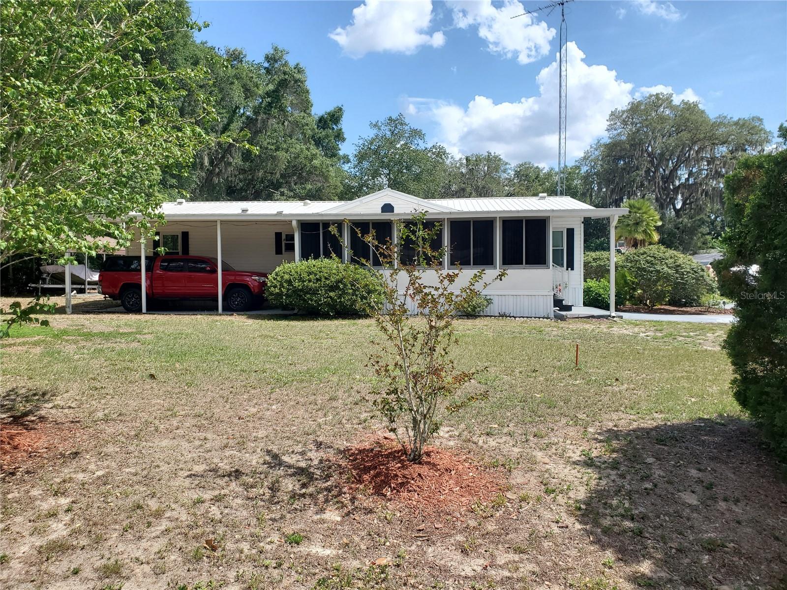 PRICE IMPROVEMENT!!!Motivated SELLERS!! Step into affordable Florida living in this well-cared-for 1998 manufactured home w/ a metal roof on a dead-end street meaning no noisy traffic in front of your home. This 3/2-bedroom home is easy maintenance flooring without carpet, plus three solar tubes that fill the interior with natural light. Situated on its own oversized lot with no HOA, the property includes well and septic for added savings and convenience. Enjoy year-round swimming in the steel-sided 18-foot pool enclosed within a birdcage, allowing you to relax without bothersome bugs or mosquitoes. Dual carports provide ample space for multiple vehicles, boat storage, or recreational equipment. Be prepared for Florida weather with the included Generac generator connected to a buried 250-gallon propane tank. Additional features include RV hookups, saltwater hookup access, and storage sheds with electricity already installed. The open floor plan creates a bright and welcoming living space, while the kitchen features a convenient breakfast bar perfect for casual dining, entertaining guests, or enjoying your morning coffee. Less than 5 miles from the Villages means you have access to enjoy all the shops, restaurants and entertainment that makes this area lively and fun.  Call for your own showing today!