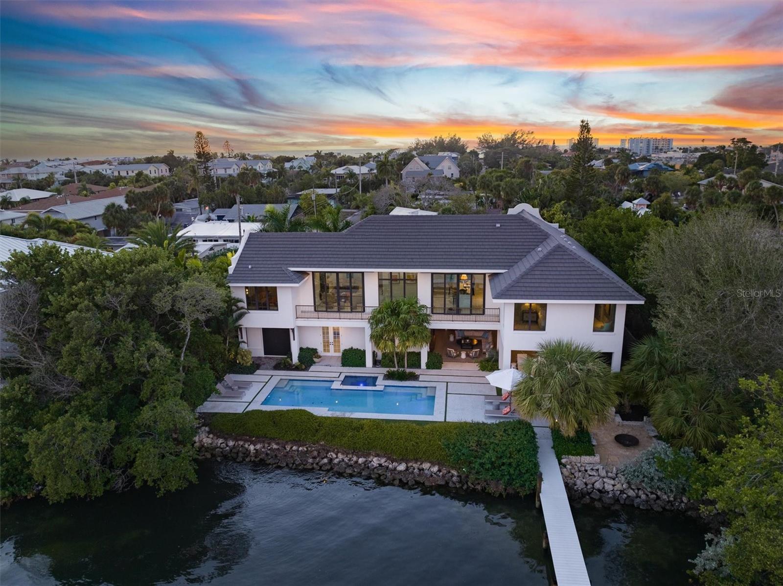 Welcome to your luxury Bayfront paradise! This stunning property offers the ultimate blend of luxury, serenity, and natural beauty with British West Indies vibes. Nestled at the end of a quiet street, the home boasts breathtaking panoramic views Tampa Bay from every angle. Featuring 4 bedrooms and 5 bathrooms there is an abundance amount of space for everyone. Beyond exquisite entry doors, a grand foyer welcomes you into somewhere very special. Step onto the meticulously landscaped grounds, designed by 2022 HGTV award winner, Landscape Architect, Craig Reynolds, the outdoors provides the ultimate private outdoor experience. Your oasis awaits with an expansive first level 1,325 Sq Ft stone patio surrounding a sparkling bay-side heated pool with spa, outdoor fire-pit, mosquito mist system, indoor/outdoor Sonos system, built-in gas barbecue grill with custom stone bar, lounge with handmade paneled TV wall.  All the exterior woodwork is Cypress, which is rot free.  Enjoy breathtaking water vistas affording the ultimate outdoor pleasure. Perfect for entertaining or simply unwinding as you listen to the gentle lapping of the waves against your private shoreline. Host fabulous cocktail hours, barbecues and pool parties; lounge with a coffee and newspaper in the shade in the covered lounge; or savor the serenity from the upper level deck overlooking the bay. The architectural design of this home is nothing short of spectacular. With 15-foot vaulted ceilings, unmatched millwork, shell reef tile floors, 10-foot doors throughout, and very detailed finishes throughout. Open the expansive impact slider doors to allow an abundance of natural light and experience a true indoor-outdoor experience with Bay breezes. The gourmet kitchen features top-of-the-line Thermadore appliances, 6- burner gas stove, large waterfall island, and a walk-in butler’s pantry with a wine fridge that makes entertaining a breeze. The primary suite is a true retreat with unobstructed sunrise and water views every morning to wake up to. With a connecting custom-built walk-in closet with adjacent bathroom suite with walk-in shower and water closet. There are blackout motorized shades for your utmost privacy.  The other 3 well-appointed bedrooms all having their own ensuite bathrooms. Beautifully designed outdoor shower offers an escape from reality, while the connecting dock provides the option for fishing or paddle boarding from your backyard, or jumping onto your boat from the 10,000 lbs lift for a sunset cruise.  Attached is a 2-car garage and plenty more parking available in the driveway.  There’s a recovery room/ 2nd garage with a custom made cold plunge, the room has an electric rollup screen that allows you to be in the tub and watch the sunrise over Anna Maria sound every morning.   The room is also wired for a sauna.  Located in the heart of Holmes Beach on Anna Maria Island, you are 2 blocks away from the Gulf of Mexico beaches, shopping at the best boutiques and dining at many restaurants close by. Newsweek released their 25 Most Popular Beach Towns in America, and Anna Maria Island Florida took the top spot. Come see it for yourself and schedule your private showing today!