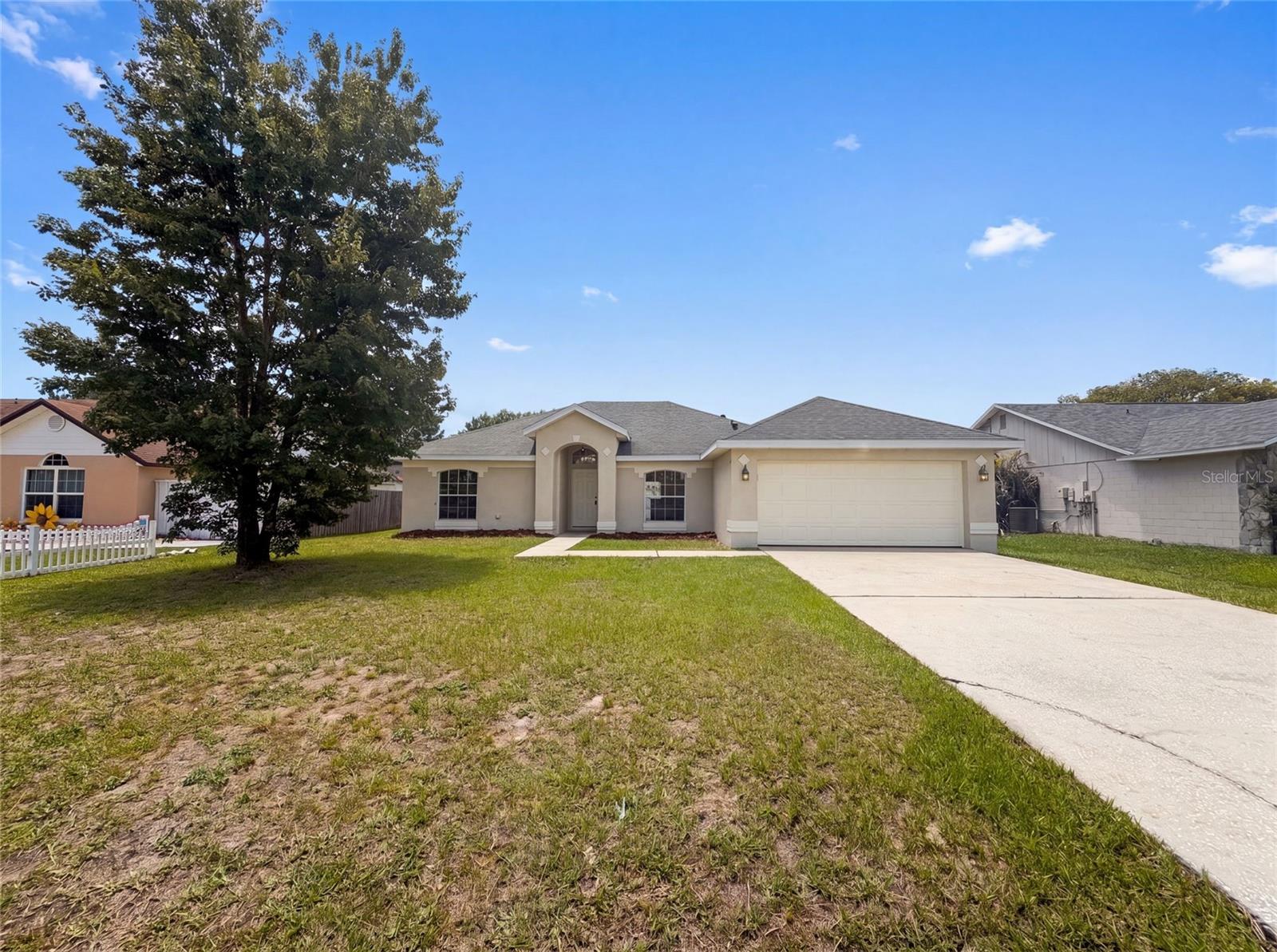 Virtually Staged. Welcome to this modern single-story residence in a desirable Kissimmee location. The home showcases an open-concept floor plan with beautiful wood-look flooring flowing throughout the main living areas, creating an inviting and spacious atmosphere. The well-appointed kitchen features white cabinetry, dark countertops, and stainless steel appliances for contemporary functionality. Multiple bedrooms, each with abundant natural light and ceiling fans, provide flexible accommodation options, complemented by full bathrooms with updated fixtures and tile finishes. The intelligent layout maximizes comfort and energy efficiency while maintaining clean, modern aesthetics throughout. Located on a generous lot with mature landscaping and an established shade tree, the property offers significant outdoor potential. This move-in ready home combines contemporary design with practical conveniences.. Included 100-Day Home Warranty with buyer activation