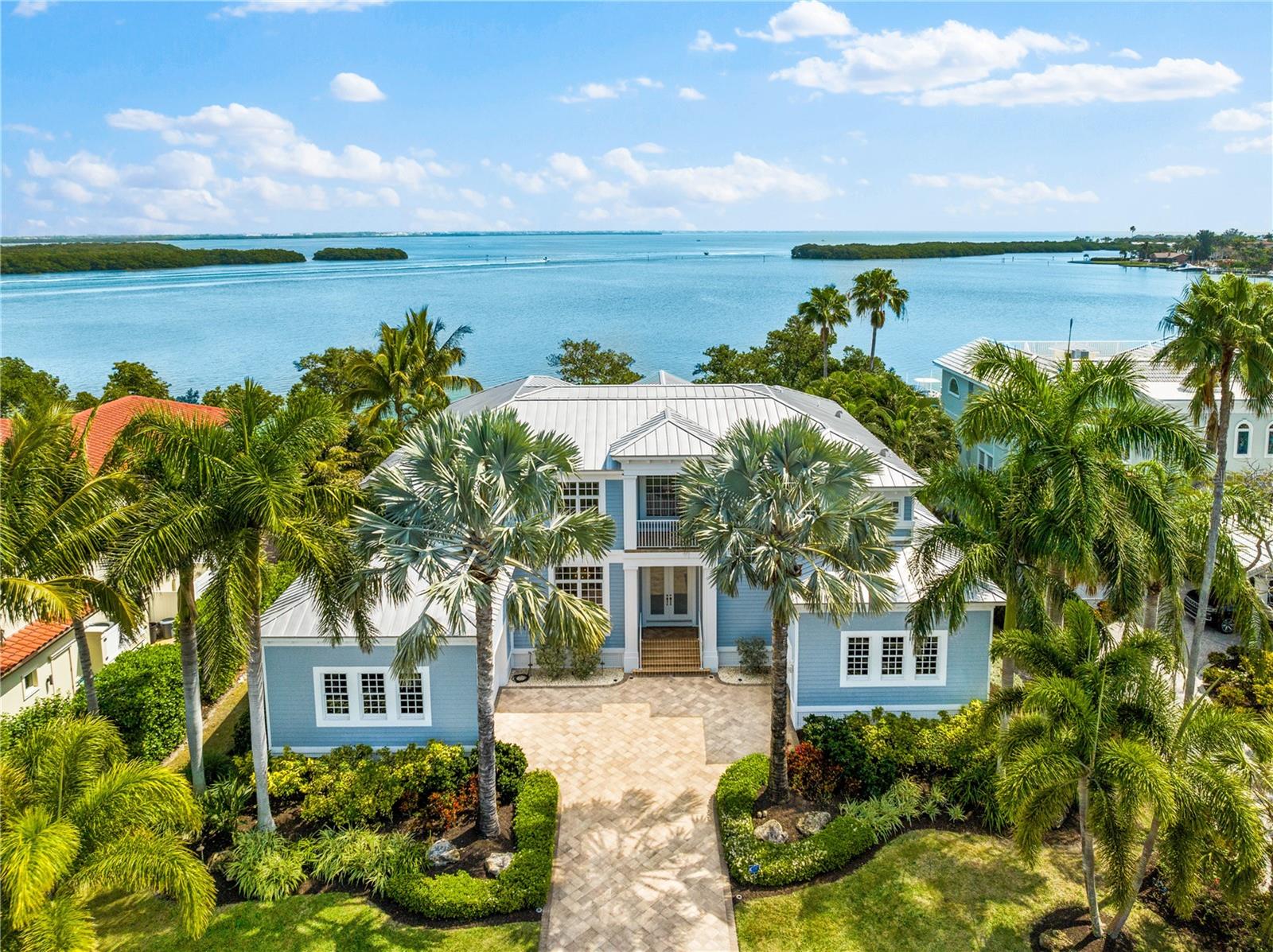 Introducing Maison d’Azur, a custom waterfront estate in the prestigious Hideaway Bay enclave on the north end of Longboat Key. WHERE COASTAL LUXURY LIVING MEETS THE BAY!  This exquisite four-bedroom, five-bath Key West-inspired residence, crafted by acclaimed builder John Cannon, seamlessly blends indoor and outdoor living to create an atmosphere of refined luxury reminiscent of a boutique hotel. Situated on over a quarter of an acre, this bayfront property commands breathtaking, unobstructed views. Enjoy the vibrant hues of sunrise and sunset over tranquil waters, with palm fronds swaying in the coastal breeze.

With a newly renovated private forty-foot-deep water dock and boat lift, Maison d’Azur is a haven for boat enthusiasts and nature lovers. Spend afternoons in the saltwater pool and evenings on the loggia as the Belt of Venus rises over Sarasota Bay. Enjoy dining from your custom outdoor kitchen, surrounded by lush tropical landscaping. Step inside to experience luxury and meticulous craftsmanship, with a grand foyer featuring soaring ceilings and custom pillars. The open floor plan connects a chef’s kitchen, equipped with Sub Zero, Miele, Fisher and Paykel, and Wolf appliances, to a spacious family room with built in cabinetry, creating an inviting atmosphere for entertaining. Archways lead to elegantly decorated formal dining and living rooms.

Ascend the private elevator to the second floor, where a great room with a custom entertainment center awaits, along with a study perfect for savoring a cognac on the captain’s porch. The expansive second floor offers a loggia and bedrooms with stunning panoramic views of the pool and Sarasota Bay. Maison d’Azur embodies exquisite taste and timeless beauty. With imported materials and innovative technology throughout, every detail has been curated for an elegant experience. This residence is sold fully furnished, with pieces selected to enhance each room’s design and ambiance.

Hideaway Bay is located on Longboat Key, an eleven-mile island off the coast of Sarasota. This enclave of only seventeen estates is steps away from the deeded beach and boasts two private tennis courts. Residents enjoy easy access to premier country clubs, golf courses, waterfront activities, dining options, and upscale shopping. Experience coastal living where every day feels like a vacation amidst the beauty and tranquility of the Gulf Coast. This property sustained no damage from the storms/hurricanes of last year. It boasts an elevation of 10.5’, ensuring you stay high and dry.
