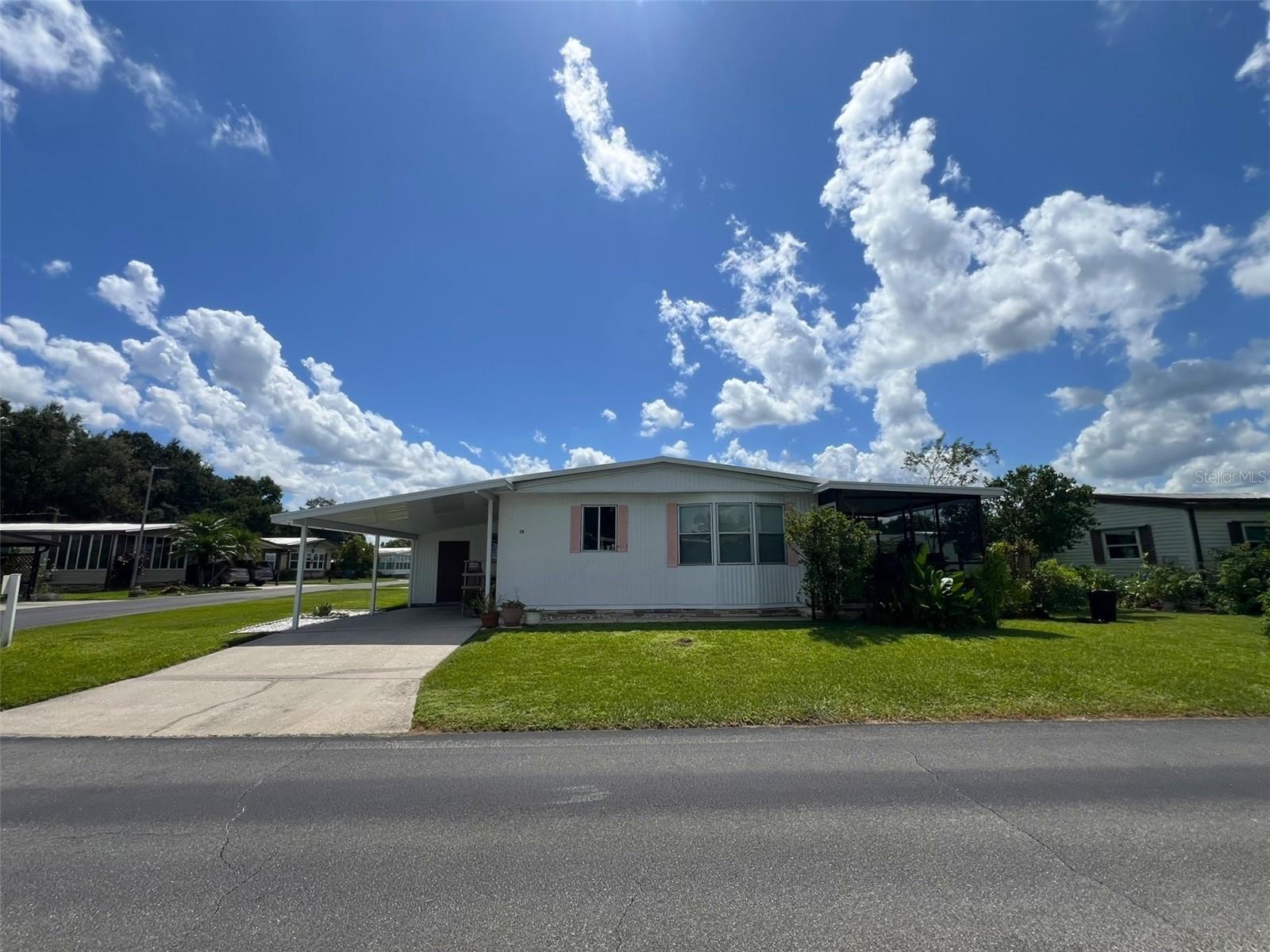 This spacious 2 Bedroom, 2 Bathroom manufactured home in the 55+ Floral Lakes Community in Bartow, Florida features double pane windows in the Primary Bedroom; a metal roof; a large Kitchen with new subflooring and finish flooring, along with newer cabinetry and a stylish oversize sink, ample storage & closet pantry; a Dinette area; a large Living Room with access to the rear screened porch. Primary Bedroom features walk in closet and en-suite bathroom with fiberglass shower. Guest bathroom features a fiberglass tub/shower combo. Luxury vinyl flooring in the common areas, carpet in the bedrooms. Full size washer and dryer (included) are located in the outdoor laundry room/workshop, under the single car carport. 
Located in central Florida, between Tampa and Orlando, this golf cart friendly community is near the Bartow Civic Center, Bartow Public Library, and Mary Holland Park. Here you OWN YOUR LAND (no lot rent) and pay low monthly HOA fees. The Floral Lakes community offers access to a stocked pond with community boat ramp and dock. Clubhouse amenities include recreation space, shuffleboard, putting green, and large heated swimming pool. Social clubs, dances, exercise, pot lucks, and MORE! Association approval is required for purchase. Call your Realtor today for more information and to schedule a showing!