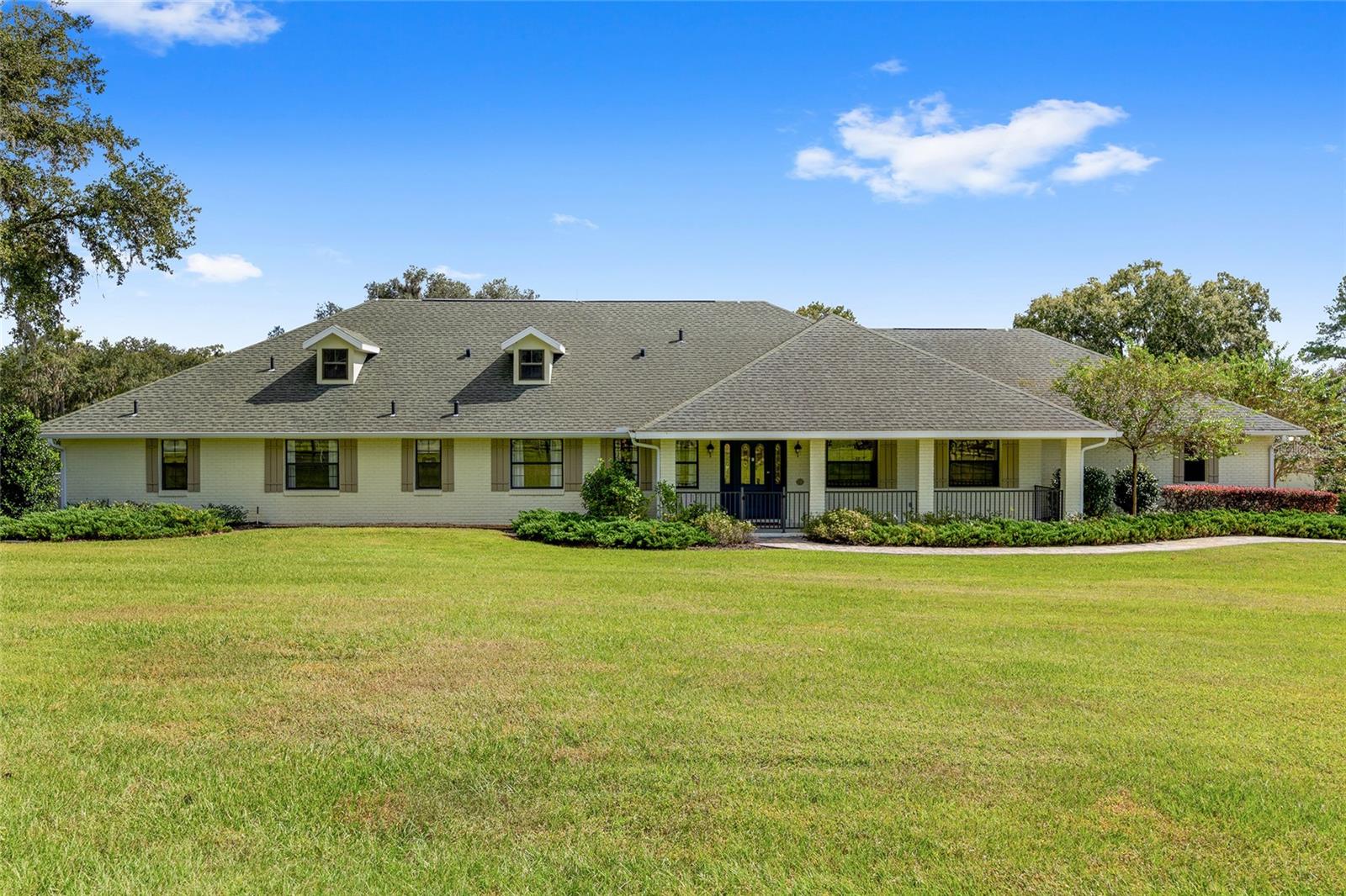 Set in the heart of northwest Ocala’s horse country, this meticulously maintained farm spans just under fourteen acres in the quiet and desirable Field of Dreams neighborhood. Ideally positioned only minutes from World Equestrian Center, HITS Ocala, and everyday conveniences, the property offers a rare blend of privacy and accessibility. A scenic, tree lined drive winds through gently rolling, manicured pastures, leading to the barn, arena, and residence. Mature landscaping surrounds the home, where a welcoming front patio and classic paver walkway create a warm first impression.
Inside, the home is bright, inviting, and recently updated, featuring three bedrooms, two and a half baths, plus a den or office. Thoughtful upgrades include cherry and cork wood flooring, refreshed finishes throughout, and abundant natural light. The great room is designed for both everyday comfort and entertaining, highlighted by cathedral ceilings, expansive windows, and a dramatic floor to ceiling wood burning fireplace. The kitchen has been completely renovated with custom cabinetry, high end appliances including a GE Profile range with air fryer, Fisher and Paykel refrigerator and dishwasher, Viking microwave, a center island with breakfast bar, and a cozy breakfast nook with bay window views overlooking the pool.
The split bedroom layout provides privacy for guests, with two generous guest rooms connected by a Jack and Jill bath with dual vanities. The primary suite offers a private retreat with its own screened lanai, two walk in closets, and a newly updated en suite bath featuring granite countertops and a walk in shower. French doors from the kitchen open to a screened patio that flows into the resort style pool area, surrounded by lush gardens, paver walkways, and built in seating ideal for relaxing or entertaining. Just off the pool, a detached guest area offers two private bedrooms, each with its own bath, along with a small exterior kitchenette, making it perfect for visiting friends or family.
Equestrian amenities are equally well planned. The farm includes five three board fenced paddocks, each with water, and a concrete block center aisle barn with five matted stalls, twenty foot ceilings for excellent airflow, a fly spray system, wash rack, and tack room. The newly installed seventy by one hundred eighty foot irrigated arena with Fleet Footing is ready for year round training. A recently added one thousand gallon buried propane tank and whole house generator provide added peace of mind during storm season. For those seeking a move in ready horse property in one of Ocala’s most sought after locations, offering tranquility without sacrificing convenience, this exceptional farm truly delivers.