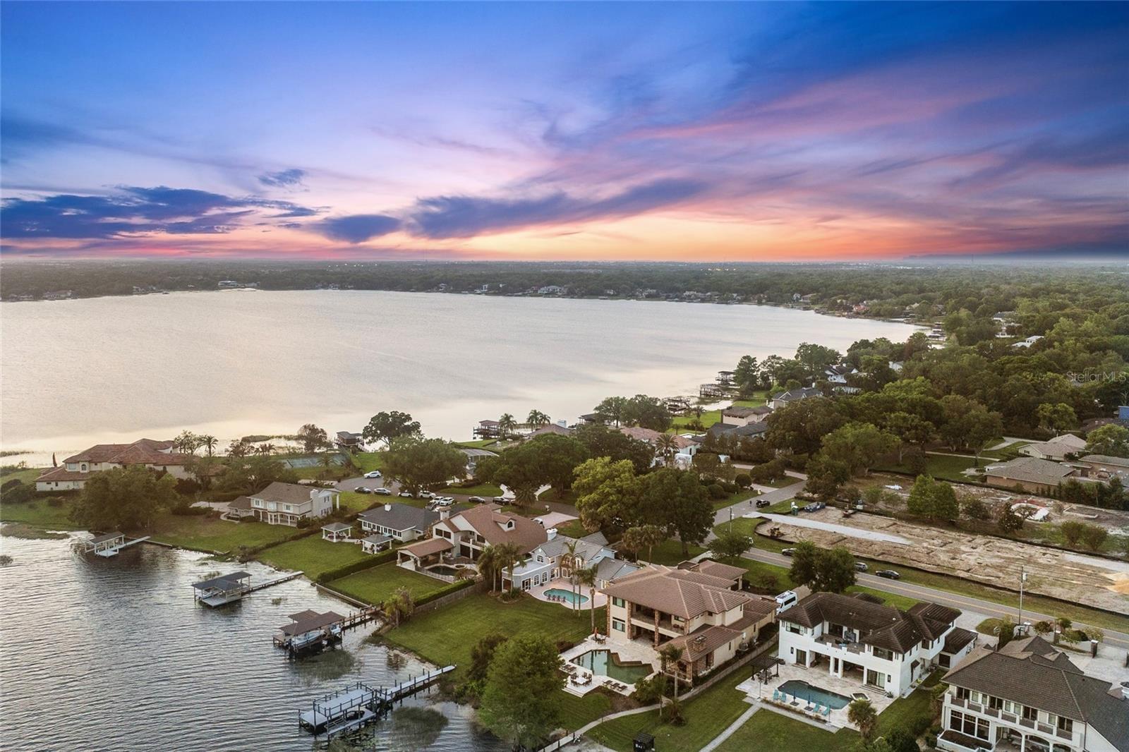 Lakefront living on the Butler Chain of Lakes in the heart of Windermere. This rare offering on Lake Down presents 100 feet of direct frontage, expansive water views and a private setting on a quiet cul-de-sac with no HOA. Set across 1.35 acres, this two-story pool home captures the essence of Windermere’s enduring lakefront lifestyle, where space, privacy, and natural beauty come together in a setting that feels refined and relaxed. From sunrise to sunset, the backdrop is nothing short of extraordinary. Sweeping views stretch across Lake Down, where calm morning waters give way to vibrant evening skies, and a nightly Disney fireworks view adds a subtle sense of wonder to the horizon. The property is thoughtfully oriented to take full advantage of its surroundings, featuring a private beach area, a two-story dock and direct access to the Butler Chain, one of Central Florida’s sought-after and interconnected lake systems, known for its recreational appeal and timeless value. Inside, the home offers a layout designed for everyday living and effortless entertaining. Spacious living and family rooms are complemented by an open kitchen appointed with granite countertops and stainless steel appliances, creating a central gathering space that flows naturally to the outdoors. A dedicated office or den provides flexibility for work or quiet retreat, while an upstairs loft captures elevated, panoramic views of Lake Down, an ideal setting for a secondary lounge, media space or creative studio. The outdoor experience is equally compelling. A resort-style pool anchors the backyard, accompanied by a screened porch and expansive lawn that extends toward the water’s edge. The setting invites relaxed afternoons and large-scale gatherings, with ample room to further enhance or personalize the landscape. A greenhouse and additional storage add charm and functionality, supporting a variety of lifestyle needs. A second-story balcony offers yet another vantage point, where elevated lake views and evening fireworks create a memorable daily backdrop. Whether enjoying a quiet morning coffee or winding down at sunset, this space reinforces the home’s seamless connection to its environment. Positioned in a peaceful and private location, yet just moments from renowned restaurants, shopping and everyday conveniences, the property offers a rare balance of seclusion and accessibility. Its location on one of the desirable stretches of Lake Down further underscores its long-term appeal. This is a compelling opportunity to enjoy the home as it exists today or to reimagine the site as an exceptional custom waterfront estate. In a setting defined by natural beauty, established luxury and enduring demand, properties of this caliber and positioning are increasingly rare.