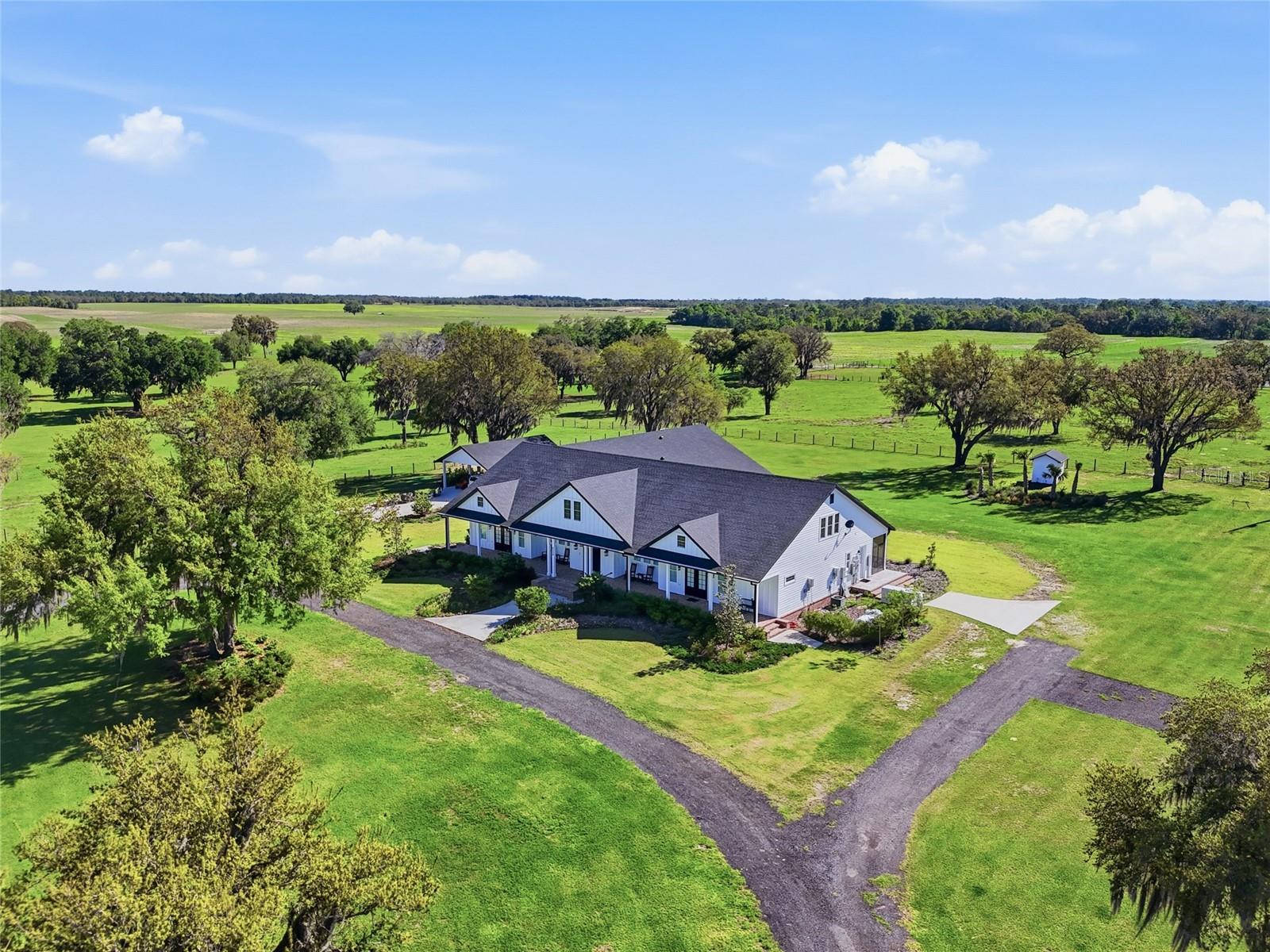 Experience the pinnacle of country living with this extraordinary 1,200+ acre turnkey farm, a rare legacy property that seamlessly blends luxury, scale, and agricultural productivity. From the moment you enter through the private, oak-lined drive, you’re welcomed into a breathtaking landscape thoughtfully designed for both beauty and efficiency. Fully fenced and meticulously improved, this working farm is equipped for immediate operation and long-term success. The infrastructure is second to none, featuring a horse barn, an impressive 12,000-square-foot packing shed, multiple hay and equipment barns, irrigation pivots and risers, cow wells, a windmill, pond, and kennels. With three separate access points, the property offers exceptional versatility, whether you’re expanding agricultural operations, managing livestock, or creating a private estate compound. At the heart of the property sits a stunning custom-built residence completed in 2024, offering 5,429 square feet of heated and cooled living space, including a private attached mother-in-law suite with its own entrance. This thoughtfully designed home features 5 bedrooms and 5.5 bathrooms, with every detail curated to elevate comfort and style. A full-length front porch spans the home, providing the perfect setting to take in sweeping views and unforgettable sunsets. Inside, timeless farmhouse charm meets refined craftsmanship with stained wood beams, brick accents, shiplap, wainscoting, and high-end designer finishes throughout. The kitchen is truly the centerpiece, boasting a large island and an exceptional butler’s pantry complete with abundant storage, prep space, sink, commercial-sized refrigerator, and ice machine—perfect for entertaining on any scale. Spacious living areas and ample storage can be found in every room, offering both functionality and elegance. The luxurious primary suite serves as a private retreat, featuring direct porch access and a spa-inspired bathroom with dual vanities, extensive storage, and a soaking tub set within an expansive walk-in shower. A versatile office with a full bath and walk-in closet can easily function as an additional bedroom. For added peace of mind, the home also includes a private, code-secured safe room. Outdoor living is equally impressive, with a screened-in porch designed for year-round enjoyment. Complete with a fireplace, outdoor kitchen, and generous entertaining space, it’s the perfect place to relax and take in the property’s picturesque surroundings. A detached carport with enclosed storage adds convenience. In addition to the main residence, the property includes two additional homes—a 2,400-square-foot residence built in 1998 and a 1,236-square-foot home built in 1983—as well as a 1,536-square-foot apartment. These provide endless opportunities for multi-generational living, rental income, or housing for farm staff. Formerly a highly successful peanut farm, this property carries a rich agricultural history and is primed for continued production or future expansion. Whether you envision a thriving farming operation, equestrian estate, or private family compound, this one-of-a-kind offering delivers unmatched potential. A property of this caliber is more than a purchase—it’s an investment in a lifestyle, a legacy, and a future where luxury meets the land.