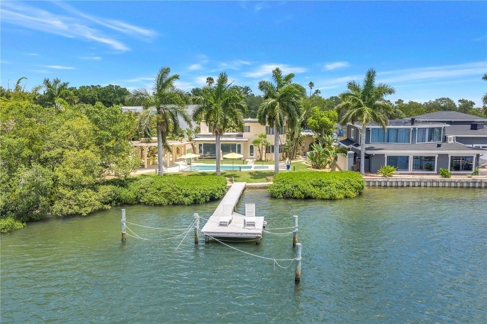 Tucked away on a quiet cul-de-sac in the rapidly evolving Innovation District near downtown St. Petersburg, this Tropical Modern/Mid-Century waterfront home offers open sailboat water access, a private dock, and beautifully landscaped grounds designed for both relaxation and entertaining. The resort-style outdoor living space features a heated saltwater Quartz-Tec pool, hot tub, gas fireplace, and an expansive pavillion, all surrounded by generous yard space and serene water views. Hurricane-impact doors and windows provide peace of mind, while newer exterior paint, irrigation, pool equipment, HVAC systems, electrical updates, and newer appliances add modern convenience throughout.
Inside, the home showcases soaring high ceilings with exposed beams, tile flooring, an interior gas fireplace, and an open-concept design filled with natural light. The updated 2024 kitchen is both stylish and functional, featuring stainless steel appliances, double ovens, a newer Thermador refrigerator, Wolf cooktop, open glass cabinetry, an island, with a spacious layout ideal for entertaining. With four bedrooms and three and half spacious bathrooms, the home offers Jack and Jill bedroom suites upstairs including a luxurious main-floor suite with a private sitting room/office and laundry room. Unique upstairs and downstairs turret spaces add architectural charm and character to this one-of-a-kind residence. Conveniently located near downtown St. Pete, award-winning beaches, shopping, dining, and major interstates, this private waterfront retreat perfectly blends timeless design with modern luxury.