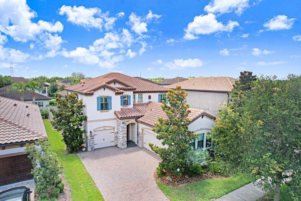 Welcome to this exceptional former model home located in the highly sought-after community of Starkey Ranch. This beautifully upgraded Homes by WestBay Ballast Point floorplan offers 4 bedrooms, 3 full bathrooms, a split 3-car garage, sparkling pool and spa, versatile flex space, upstairs laundry room, and designer finishes thoughtfully curated throughout. From the moment you enter, you are welcomed by an impressive foyer and elegant dining room featuring custom trim work, designer wallpaper accents, tray ceilings with soft blue hues, and a stunning statement chandelier that immediately sets the tone for this impeccably designed residence. At the heart of the home, the gourmet kitchen showcases granite countertops, rich wood cabinetry, GE Profile appliances, built-in oven and microwave, gas cooktop, custom vent hood, Samsung refrigerator, oversized center island with seating, designer pendant lighting, and a perfectly positioned dry bar area ideal for entertaining. The kitchen flows seamlessly into the spacious grand room filled with natural light and tranquil views of the pool and outdoor living space. Just off the main living area is a dedicated flex space, perfectly suited for a home office, study area, or creative retreat. A first-floor guest bedroom and full bathroom provide an ideal setup for visitors or multigenerational living. Upstairs, a generously sized bonus loft creates a wonderful separation between the secondary bedrooms and the private primary suite, offering endless flexibility as a media room, playroom, or additional living space. The upstairs laundry room adds everyday convenience, while two additional bedrooms feature ample closet space, abundant natural light, and access to a thoughtfully designed secondary bathroom with dual vanities and a private shower area. The luxurious primary suite serves as a private retreat featuring electric shades and a spa-inspired ensuite bathroom with separate vanities, soaking tub, oversized walk-in shower, spacious walk-in closet, and a private water closet enhanced with a premium TOTO toilet for added comfort and sophistication. Step outside to your own backyard oasis complete with a sparkling screened-in PebbleTec pool and spa, expansive paver patio, pet-grade turf, and a turf putting green, creating the perfect setting for entertaining, relaxing, and enjoying the Florida lifestyle year-round. Additional upgrades include a water softener system, EV charger in the garage, tile roof, manicured landscaping, and a split 3-car garage that further enhance both the curb appeal and functionality of the home. As an added bonus, the sellers are including a highly upgraded, road-ready 6-person golf cart featuring a premium lithium battery, upgraded light and sound system, and custom enhancements with an estimated value of $12,000. Ask for the feature flyer for full details on this incredible addition. Conveniently located near the K-8 school, parks, playgrounds, trails, community pools, restaurants, shops, and everything Starkey Ranch has to offer, this exceptional former model home perfectly blends luxury, comfort, and convenience in one of Tampa Bay’s most desirable master-planned communities.