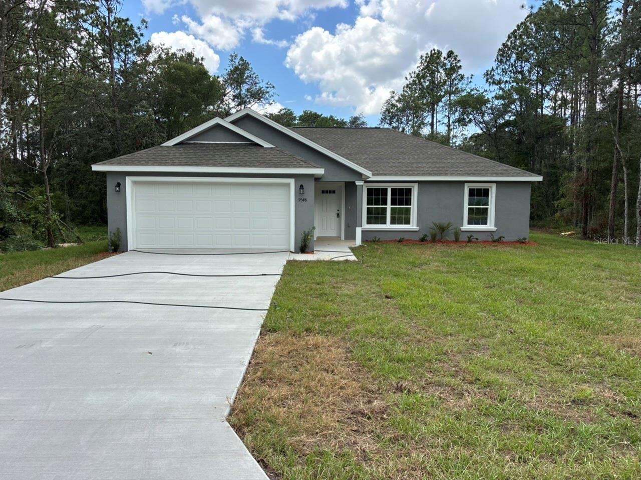 NEW CONSTRUCTION. MOVE-IN READY! Welcome to the Key West Model in Citrus Springs, a beautifully finished 3-bedroom, 2-bathroom home with 1,405 square feet of comfortable living space. Built with durable concrete block construction, a 30-year architectural shingle roof, energy-efficient double-pane windows, and a 10-year structural warranty, this home is designed for lasting value and peace of mind. The main living area features vaulted ceilings that create an open, bright feel, with luxury vinyl plank flooring throughout the home for a clean and modern look. The kitchen offers stainless steel appliances, custom white shaker cabinets with soft-close drawers, granite countertops, a pantry, and ample space for everyday living and entertaining. The bathrooms feature granite countertops and high-quality finishes that complement the home’s fresh style. Enjoy washer and dryer hookups, a covered patio, and an attached 2-car garage with opener and remotes. High and dry in flood zone X with no flood insurance required, and no homeowner association fees for added ownership freedom, this Citrus Springs home is ready for you to move in and enjoy.