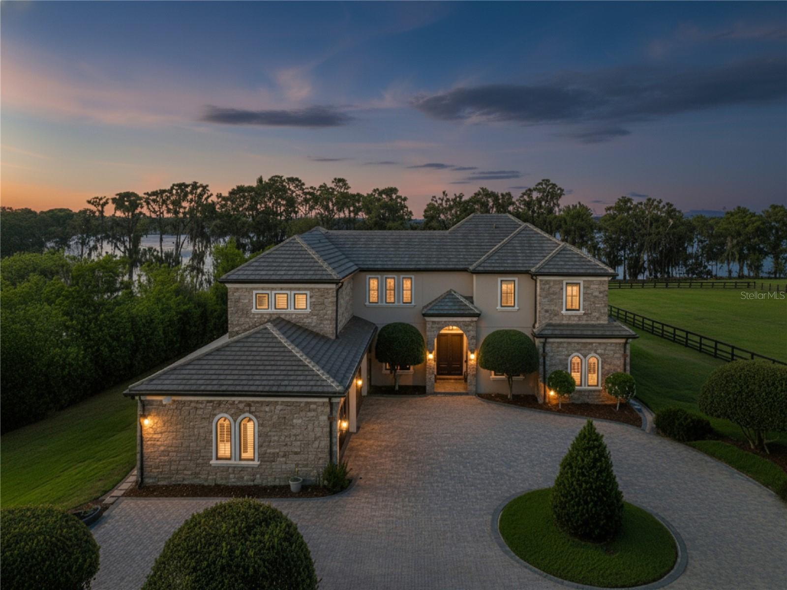 One or more photo(s) has been virtually staged. PRIVATE LAKEFRONT ESTATE ON PRISTINE LAKE MILLS

Tucked behind a winding 700-foot gated drive, this extraordinary 7.22-acre lakefront estate offers an unparalleled blend of luxury, privacy, and resort-style living on the crystal-clear, spring-fed waters of Lake Mills, one of Central Florida's most exclusive private ski lakes. With approximately 152 feet of waterfront, NO HOA, and zoning that allows for agricultural exemption, this property presents a rare opportunity to own one of Seminole County's most unique private waterfront retreats.

The custom-built residence showcases soaring 24-foot coffered ceilings, stacked stone architectural details, rich pecan wood flooring, and breathtaking panoramic lake views. Designed for both everyday living and entertaining, the home features a formal dining room, expansive family room with stone fireplace, private office, oversized en-suite bedrooms, and a chef's kitchen appointed with imported Taj Mahal marble, custom cabinetry, flush built-in refrigeration, dual ovens and sinks, and a large center island overlooking the waterfront.

The first-floor primary suite offers a peaceful escape with unobstructed lake views, while an additional downstairs bedroom and full bath provide ideal accommodations for guests or multigenerational living.

Outdoor amenities create a true private resort experience, featuring a summer kitchen, expansive entertaining spaces, gazebo, 100+ foot dock, 23+ foot boat lift, dual jet ski lifts, and direct access to boating, water skiing, wakeboarding, paddleboarding, fishing, and endless days enjoying one of Central Florida's premier recreational lakes.

A standout feature of the property is the detached barn and recreation building. While currently configured for equestrian use, the structure offers exceptional flexibility as a luxury golf simulator lounge, game room, sports bar, fitness studio, executive office, workshop, guest retreat, or additional entertainment space. With poured concrete walls, spray foam insulation, climate-controlled areas, and substantial infrastructure already in place, the possibilities are endless. Brand new slate roof and hurricane proof double pane doors and windows. 

Conveniently located just minutes from Oviedo, UCF, major expressways, Downtown Orlando, Orlando International Airport, world-class dining, shopping, and Florida's renowned beaches, this exceptional estate offers the perfect balance of privacy and convenience.

Rarely do properties combine significant acreage, private ski lake frontage, luxury improvements, and limitless lifestyle opportunities in such an extraordinary setting. This is more than a home—it is a destination designed for unforgettable memories and exceptional living.