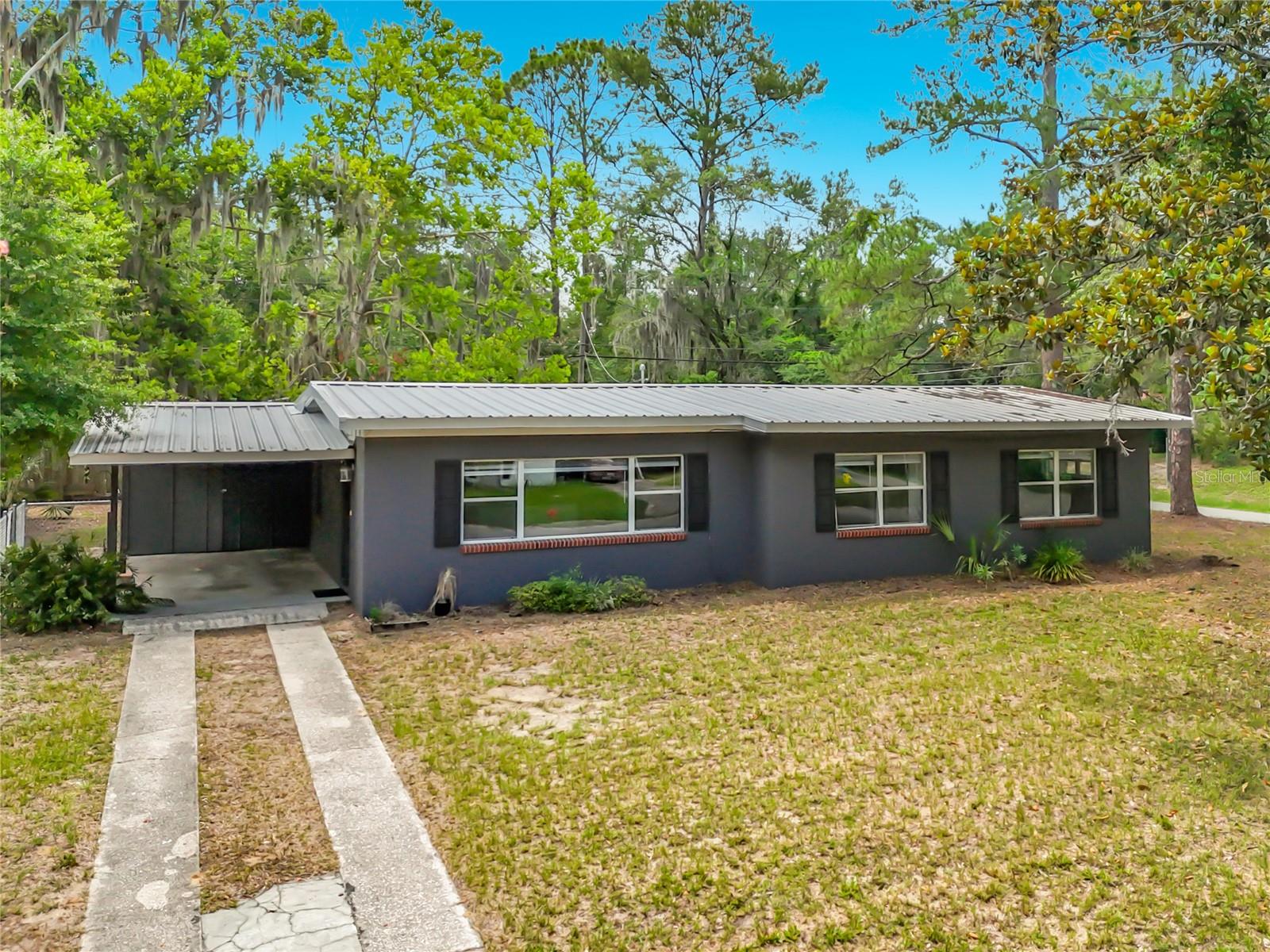 Well maintained inside and out, this Golf Club Manor home is located in a sought-after location in NW Gainesville, right off Newberry Road and NW 34th Street corridor, perfect for quick commutes no matter where you need to go. 
Built in 1956, this concrete block, 3 bedroom, 2 bath home has all of the major mechanicals and big ticket items already taken care of for you: 2011 duct work, 2011 updated kitchen, a 2011 HVAC, 2011 energy-efficient windows, 2024 water heater, 2011 roof, 2022 carpet in bedrooms, 2026 luxury vinyl plank in living/dining room, a new GRU city clean out connection in 2024! 
With nearly 1400 SF under air, this home lives large with its open floor plan. Enter the home via the attached 253 SF oversized 1 car carport. The family room is open to the kitchen and dining space. With the attached 190 SF flex space on the back, the entire living space and kitchen area is light and bright with the home’s east, south and west facing windows. This flex space has a vaulted ceiling, ceramic tile floors, several west facing windows, a door that leads to the front end of the carport where the laundry closet is located, and a tongue and groove accent wall for that MCM flair. 
The kitchen has real wood cabinetry, and a breakfast bar for casual eating or additional seating while entertaining. Remodeled in 2011, the wall between the kitchen and the living space was removed, so that the flow to the house is now open. The kitchen has the same ceramic tile as the flex room; while the dining and family room areas have brand new luxury vinyl plank flooring. In the bedroom hallway you will find the guest bath on the left that serves the two guest rooms. At the end of the hallway is the master bedroom complete with its own ensuite bathroom. 
This home is situated on a corner .24-acre lot with easy access to Newberry Road to the south, NW 34th Street to the east, and NW 8th Avenue to the north. In addition to the driveway to the carport, there is another access point on the north side of the lot for additional parking. And a portion of the backyard was fully fenced in 2025, bring all of the furry friends! 
Golf Club Manor is within biking and walking distance to the all-new Publix Westgate plaza on NW 34th Street and the Royal Park Plaza to the west. UF Health is less than 4 miles away, North FL Regional under 2.5 miles, and for those Gator football and basketball fans, less than 5 minutes/under 2 miles to the football stadium and O’Connell Center – all of which makes this house a great investment property or a comfortable home for many years to come. And all with no HOA fees!