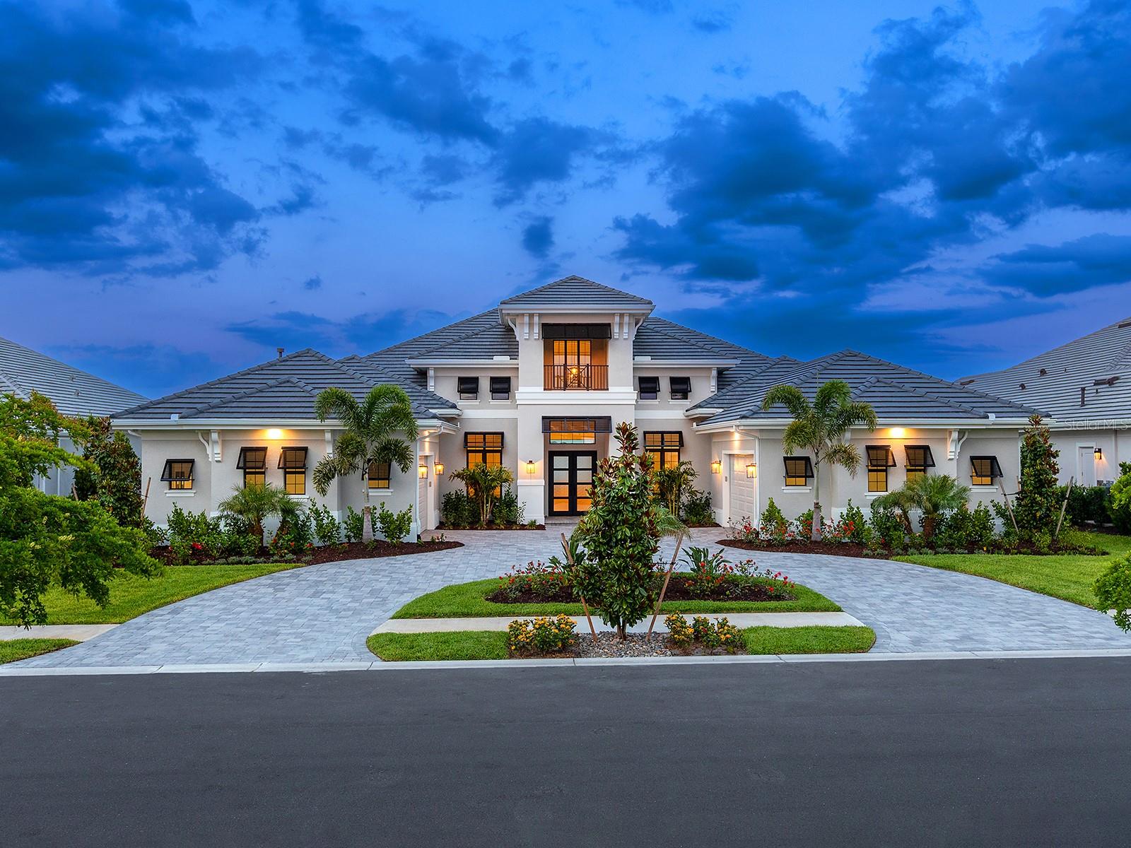 Set within the prestigious community of Wild Blue at Waterside, this newly constructed and never-occupied residence by Stock Luxury Homes is a rare offering—thoughtfully curated, richly appointed, and notably priced below reproduction. Showcasing a refined coastal aesthetic and an array of elevated upgrades, the home presents over 4,369 square feet of interior living space and nearly 7,000 square feet in total, all perfectly positioned on an expansive lakefront homesite with sweeping, uninterrupted water views and a serene sense of privacy.
The Clairborne II floor plan is both elegant and functional, designed to accommodate everyday living as effortlessly as grand-scale entertaining. The residence features three en suite bedrooms, four full baths, one half bath, a private study, an expansive bonus room, and a versatile exercise room or secondary office. A dramatic double glass and iron entry introduces a light-filled great room adorned with custom built-ins, architectural beam detailing, and a wall of disappearing sliding glass doors that seamlessly extend the living space outdoors.
The designer kitchen is a statement of both form and function, appointed with premium JennAir appliances including double wall ovens and a six-burner natural gas cooktop. A substantial center island anchors the space, complemented by double-stacked wood cabinetry, under-cabinet lighting, a full-height backsplash, and a thoughtfully designed walk-in pantry. The kitchen flows effortlessly into the casual dining area, while the formal dining room—enhanced by a striking backlit feature wall—creates an inviting setting for more refined gatherings.
Crafted for entertaining, the bonus room offers a built-in wet bar, dual storage closets, beamed ceiling, and French doors that open to the lanai. The primary suite is a tranquil retreat, complete with a private sitting area, dual walk-in closets, and a spa-inspired bath featuring Cambria stone countertops, a freestanding soaking tub, and a walk-in shower with floor-to-ceiling tile and integrated lighting. Subtle yet impactful design elements—including backlit accent walls in both the primary bath and formal dining room—add a layer of sophistication throughout. Additional highlights include a private office with glass French doors, two beautifully appointed guest suites with en suite baths, and a flexible exercise room with direct lanai access. Oversized 31-inch porcelain tile flooring extends throughout the main living areas, enhancing the home’s clean, contemporary lines. Outdoor living is equally compelling. The screened lanai features a porcelain-tiled gas fireplace, pre-plumbing for a future outdoor kitchen, and generous space to design your custom pool overlooking the mile long lake. The home is further complemented by a four-car split garage, circular driveway, tile roof, crown molding, solid-core interior doors, tray ceilings with custom detailing, and provisions for reverse osmosis and whole-home water filtration. This is a rare opportunity to own a newly built, premier lakefront home of exceptional quality and design in one of Wild Blue’s most exclusive community at this price. The upcoming 25,000-square-foot resort-style clubhouse will feature private dining, a theater, fitness studio, golf simulator. Outdoors, enjoy a spectacular pool complex with a resort-style pool, lap pool, yoga lawn and a putting course. The Midway Sports Complex offers pickleball,  tennis courts, basketball, a dog park, and more.