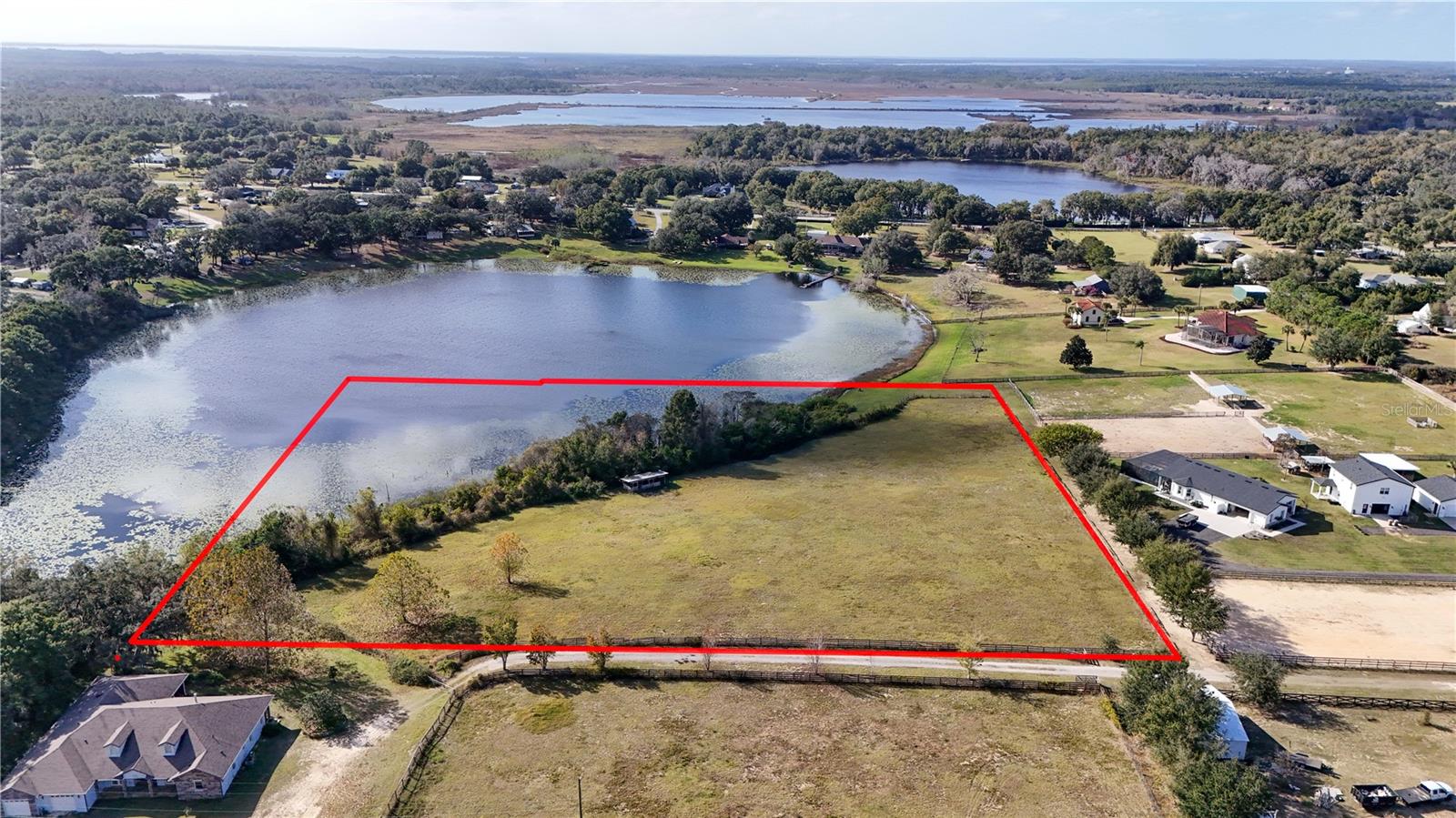 A rare opportunity to own a high and dry 5-acre country estate parcel in a highly sought-after rural setting, surrounded by well-kept neighboring properties and located in the county just beyond city limits. This land offers the freedom and privacy of true country living with no HOA, no deed restrictions, and no builder requirements. Thoughtfully zoned for horses and agricultural use, the property easily accommodates barns, workshops, RVs, boats, and other recreational pursuits. Direct Lake frontage adds to the estate appeal, ideal for quiet mornings fishing, kayaking, or enjoying the natural beauty of the water. Centrally located yet wonderfully private, the property is approximately one hour from Orlando International Airport and the renowned World Equestrian Center in Ocala, making it equally suited for a refined rural residence or an equestrian-focused retreat. An exceptional setting to create a timeless homestead or legacy property, where space, freedom, and natural beauty come together. Lot is 6.3 total acres with 1.3 acres of wetlands