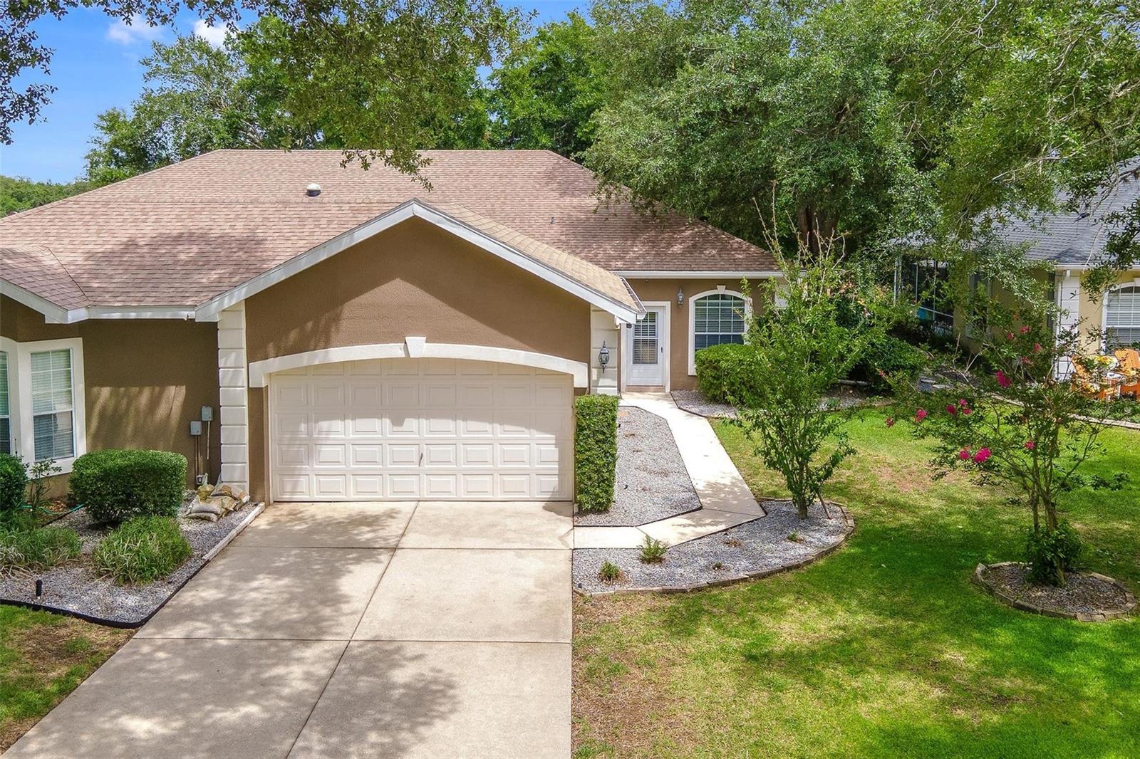 Virtually Staged. 2 PRIMARY SUITES! 1,500 SF villa with NO CARPET, remodeled baths, split floor plan in a gated golf community near The Villages! Affordable Florida living with incredible amenities and exceptional value! Welcome to the gated golf community of Harbor Hills. One of the most unique neighborhoods you'll find in Lady Lake, where beautiful tree-lined streets lead you home. Offering an incredible opportunity to enjoy a country club lifestyle at an affordable price, this villa delivers outstanding value without sacrificing space, comfort, or amenities. From the moment you arrive, you'll appreciate the charm, convenieve, and lifestyle this community has to offer. Step inside this 2-bedroom, 2-bath villa featuring a desirable open floor plan with vaulted ceilings. The spacious living room overlooks the dining area and galley kitchen while offering a built-in entertainment center and sliding glass doors leading to the rear lanai, creating the perfect space for relaxing or entertaining. The galley kitchen offers plenty of cabinet storage, a large closet pantry, and overlooks both the dining and living areas so you're always part of the conversation. One of the most exceptional features of this home is that both bedrooms are true primary suites—no more arguing over who gets the "better" bedroom! Even better, each suite has its own dedicated air conditioning unit, allowing everyone to set their own perfect sleeping temperature. Primary Suite #1 features laminate wood flooring, a spacious walk-in closet, bay windows, and a sliding barn door leading into the remodeled ensuite bath complete with a double vanity and large tiled no-step walk-in shower. Primary Suite #2 offers incredible flexibility with its own private entrance, built-in closet, and wet bar with a mini refrigerator, making it ideal as a guest suite, home office, hobby room, or multigenerational living space. The remodeled second bathroom features a  tiled shower/tub combination. Enjoy your morning coffee or unwind in the enclosed rear lanai overlooking the backyard, where you'll find mature lime and grapefruit tree adding both beauty and fresh fruit to your Florida lifestyle and you'll find Plum tree in the front yard.  Additional features include a 2-car garage and numerous updates, including:Roof (2017), Dedicated HVAC for the second primary suite (2022), Irrigation system approximately 2–3 years old, Luxury vinyl flooring in dining, living room, and primary suite #2. Required Social Membership is $251 monthly providing access to the Country Club, fitness center, Junior Olympic swimming pool, tennis courts, racquetball, restaurant, social clubs, and more creates a lifestyle you'll love. Finding a home with two true primary suites, thoughtful updates, resort-style amenities, and this much value at such an affordable price is rare. Whether you're looking for a full-time residence, seasonal getaway, or investment opportunity, this is your chance to enjoy the Florida lifestyle near The Villages.