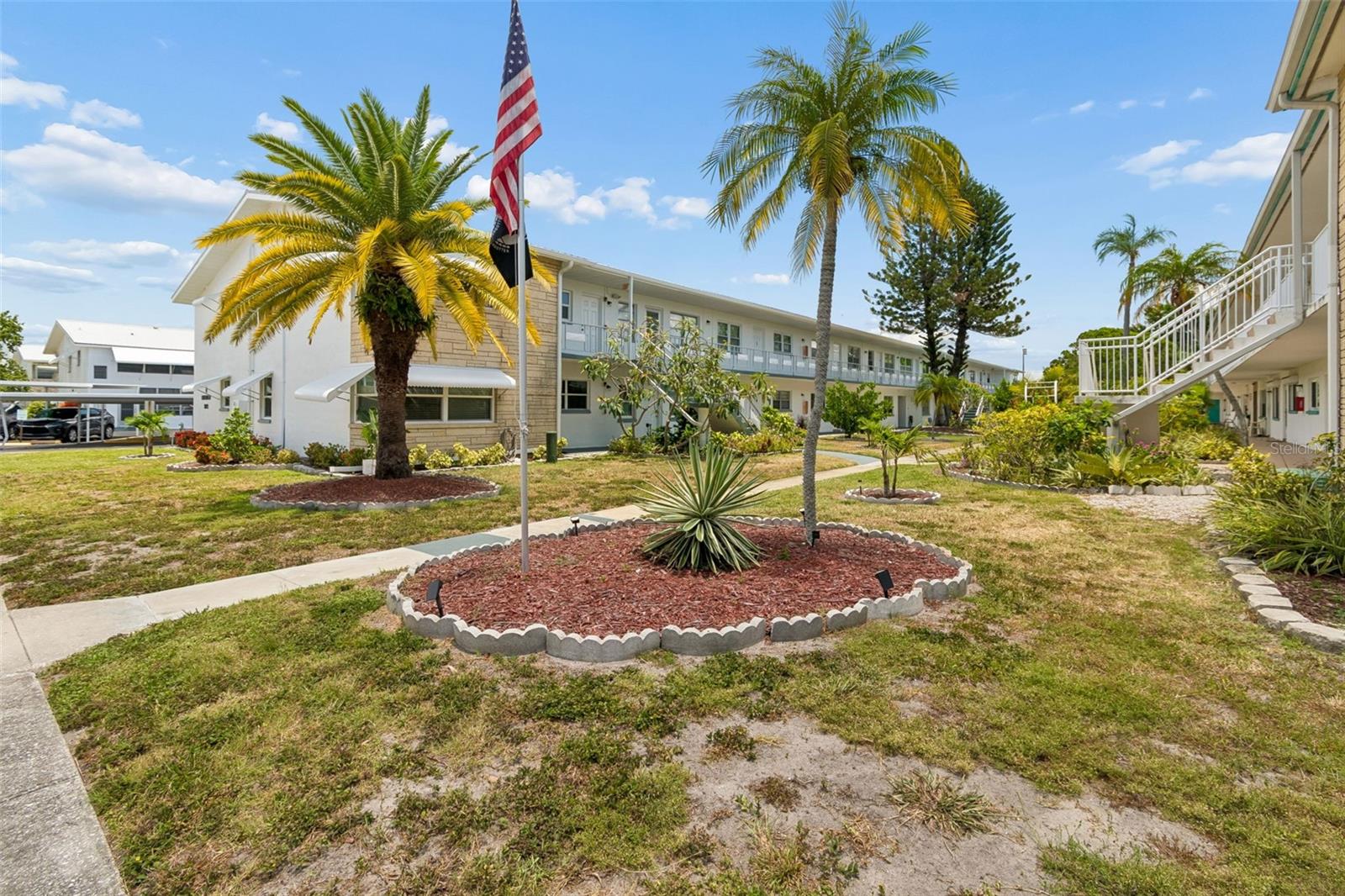 Welcome to this spacious and well-maintained 2-bedroom, 2-bath ground-floor condo in the desirable Emerald building of the Town Apartments North 55+ community. Offering approximately 950 square feet, this light-filled home features a comfortable living and dining area, an enclosed Florida room for additional living space, and a functional kitchen with ample cabinetry and included appliances. Ceramic tile and vinyl flooring provide easy maintenance throughout. Enjoy the convenience of an assigned carport, guest parking, and a location just steps from beautifully landscaped grounds. The monthly condo fee includes cable, water, sewer, trash, exterior maintenance, building insurance, reserves, and community amenities, making for truly low-maintenance living. Residents enjoy a heated pool, clubhouse, recreation facilities, shuffleboard, and an active social calendar. Ideally located near shopping, restaurants, medical facilities, public transportation, downtown St. Petersburg, and the Gulf beaches.