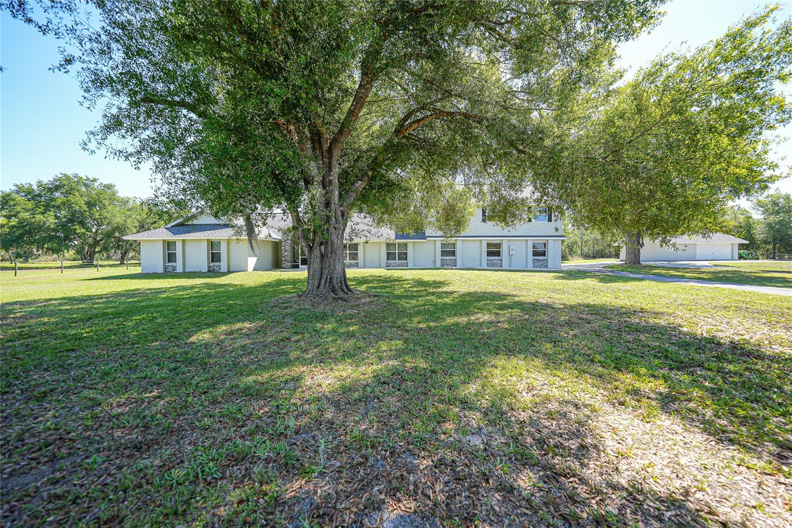 SELLER SAYS SELL!! Welcome to your private country estate, perfectly situated on 12.57 acres of picturesque land designed for both luxury living and functionality. As you arrive, a long driveway leads you to this impressive two-story home offering 4,730 square feet under air and over 6,400 total square feet. A screened and covered front entry welcomes you in through grand double doors, setting the tone for the elegance found throughout. Inside, you’ll find a spacious open floor plan featuring luxury plank tile flooring, soaring ceilings with beautiful wood accents, and an abundance of natural light pouring in through French doors that showcase peaceful views of the backyard. The living area is centered around a striking wood-burning fireplace with custom accent shelving, creating a warm and inviting focal point for gathering and entertaining. The baker’s kitchen is truly the heart of the home, designed with both style and function in mind. A massive 16-foot island provides seating for eight, complemented by extensive cabinetry with all lower cabinets featuring convenient pull-outs or drawers. Enjoy ample counter space for cooking and baking, black stainless steel appliances, and an oversized pantry complete with pull-out drawers for maximum organization. The primary suite offers a luxurious retreat with tall ceilings, French doors, and a thoughtfully designed en suite bathroom featuring dual sinks and a walk-in shower. The impressive 26-foot-long walk-in closet with built-ins provides exceptional storage. A guest bedroom offers the flexibility of a second primary suite with its own private bathroom and walk-in closet, while all additional bedrooms are generously sized with walk-in or built-in closets. A dedicated office space includes dual built-in desks, storage, and filing cabinets—perfect for working from home. The well-appointed laundry room offers extensive cabinetry, counter space, a double bowl mop sink, and the convenience of an additional full bathroom. Upstairs, you’ll find additional bedrooms sharing a bathroom along with a large living or theater area ideal for entertaining or relaxing. The exterior of the property is just as impressive, featuring a four-car attached garage along with a detached two-car garage and workshop. The land is thoughtfully laid out with cross fenced pastures surrounding a large pond, making it ideal for animals or agricultural use. Additional features include an artisan well, an 1,850 square foot concrete pad for storage, and a second power pole with separate service and RV hookup with additional septic tank. This home is loaded with upgrades, including two recently replaced HVAC units, a whole-home reverse osmosis system for exceptional water quality, and beautifully updated bathrooms throughout. Whether you’re looking for space to spread out, bring animals, or simply enjoy peaceful country living, this extraordinary property offers it all. Schedule your private showing today!