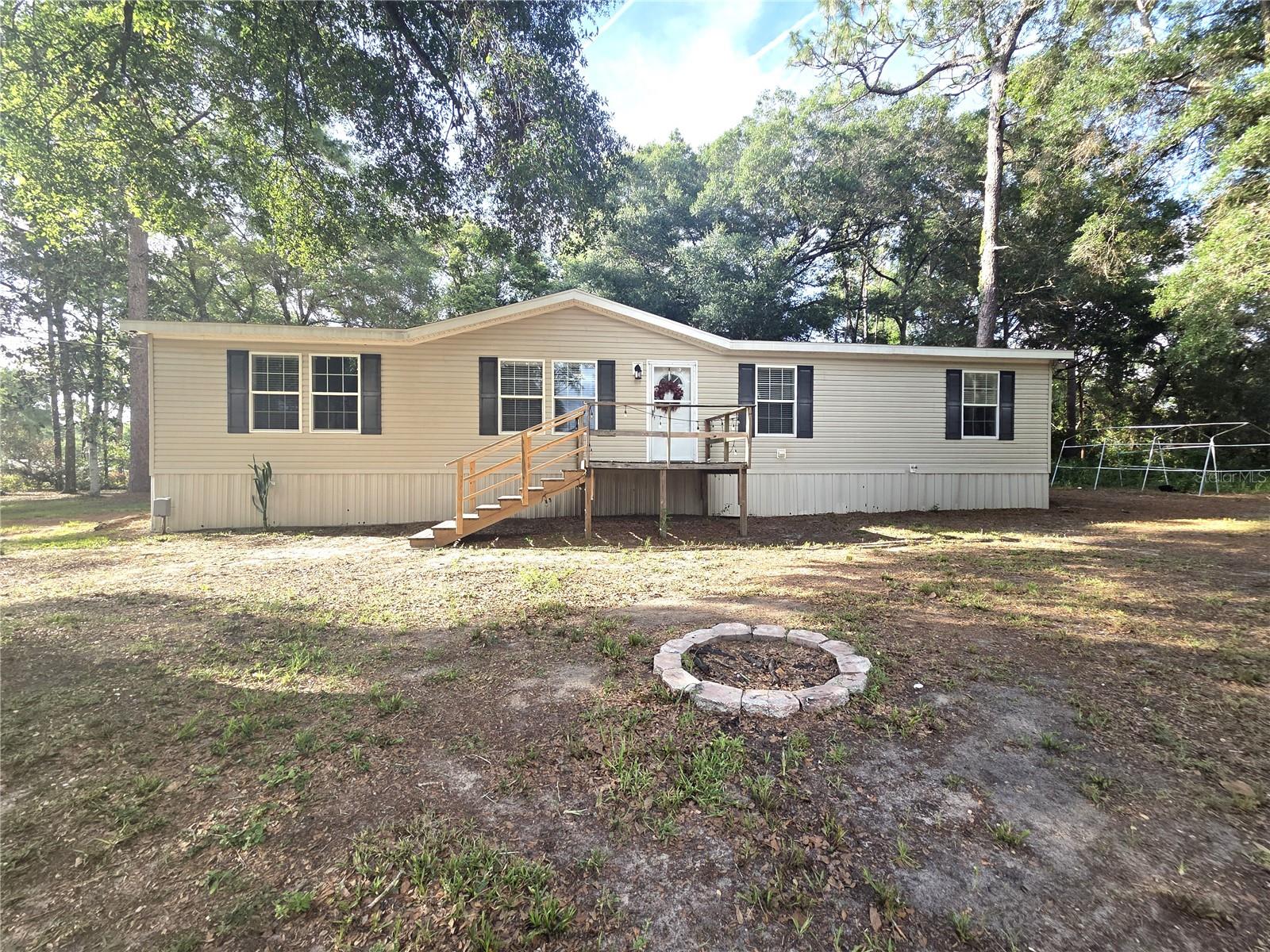 Welcome home to this spacious 4-bedroom, 2-bath double-wide manufactured home situated on 1.25 fully fenced acres with Agricultural (AC) zoning, offering plenty of room to enjoy country living while remaining conveniently close to everyday amenities. Step inside to find a thoughtfully designed split floor plan accented with crown molding throughout. The oversized kitchen is perfect for entertaining and everyday living, featuring abundant cabinet storage, a stainless steel refrigerator and dishwasher, a flat-top stove with a built-in oven, a microwave, a center island, and a cozy dining area with a sliding glass door leading to the side yard. A separate formal dining room provides additional space for gatherings and special occasions. The spacious primary suite offers a private retreat with a walk-in closet and an ensuite bathroom complete with double sinks, a vanity area, a tiled walk-in shower, and a relaxing soaking tub. The secondary bedrooms are generously sized and include built-in closets and ceiling fans for added comfort. Additional features include an indoor laundry room with extra storage and direct access to the side yard, a tankless water heater, central air conditioning, and a welcoming front porch leading to the main entrance. The property is fully fenced with a gated entrance, providing added privacy and security while offering ample space for pets, outdoor activities, or future improvements. Ideally located approximately 5 miles from the Suncoast Parkway (State Road 589) for convenient north and south access and close to restaurants, shopping, gas stations, and medical facilities. Bring your RV, boat, ATVs, and other toys, or take advantage of the Agricultural (AC) zoning to create your own garden, hobby farm, or outdoor retreat with plenty of room to enjoy the lifestyle you've been looking for.