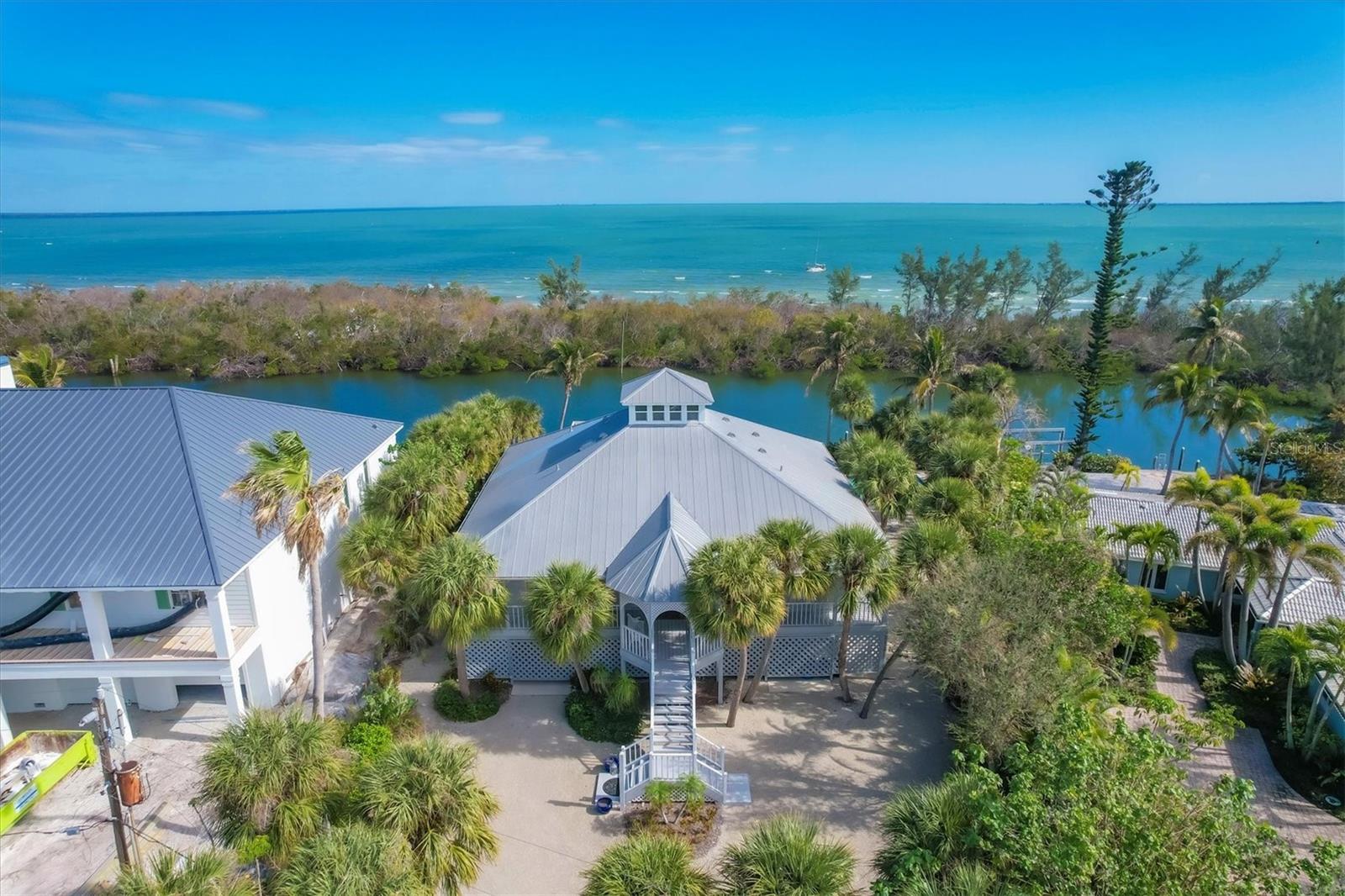 This private waterfront property is perfect for boat enthusiasts. Located on a prime deepwater channel, features include 127 feet of waterway frontage and a covered boat slip. This waterway is buffered by a stunning peninsula, home to a thriving mangrove ecosystem that plays a critical role in stabilizing the coastline and preventing erosion. Additionally, these mangroves act as a natural defense system by absorbing the impacts of storm surges and provides protection for nearby properties.  

The 2-bedroom, 2.5-bath home presents breathtaking water views and daily sunrises. A spacious loft provides additional guest accommodations, and a widow's peak offers panoramic views of the bay. Built by Dewey Noller Builders, the home reflects lasting quality and is well maintained. Inside, the residence showcases vaulted and tray ceilings with cypress wood detail that bring warmth to the living spaces. Designed in a distinctive Key West style, the home includes charming decks and porches and a large, waterside pool with coral stone details. Additional amenities include an elevator, ample storage, and plenty of covered parking. This serene waterfront lifestyle is situated on a quiet street near the village. This home did not have storm damage.