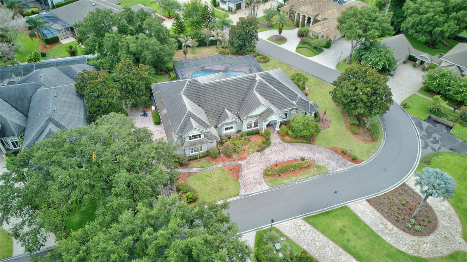 This sprawling two-story luxury pool residence showcases exceptional craftsmanship and timeless elegance, enhanced by extensive upgrades throughout and a Generac home generator. From the moment you enter, you'll be captivated by soaring tray and cathedral ceilings, rich crown molding, and refined architectural details that create an atmosphere of sophistication and grandeur.
Designed to inspire culinary excellence, the chef’s kitchen is appointed with a professional-grade gas cooktop, custom solid wood cabinetry, a hidden walk-in pantry, farmhouse sink, and a picturesque window framing serene views of Lake Winterset. A convenient built-in workstation, located near the spacious laundry room and oversized three-car garage, provides added functionality for everyday living.
The sumptuous primary suite serves as a private retreat, featuring beautiful custom built-ins, dual vanities, a chandelier-accented soaking tub, an expansive walk-in shower, and generous his-and-her custom closets. A tranquil sitting area offers the perfect space for reading and relaxation, while French doors provide direct access to the poolside lanai.
Created for effortless entertaining, the grand great room seamlessly connects indoor and outdoor living through pocketing sliding glass doors that open to a spectacular pavered lanai complete with a summer kitchen, sparkling pool, and elegant water feature. Two additional en-suite bedrooms with walk-in closets are conveniently located on the main level, while a well-appointed powder bath serves guests.
The upper level offers a private guest or in-law retreat featuring a spacious en-suite bedroom, full bath, media room, and a sizable studio or flex space overlooking the tranquil waters of Lake Winterset. Elegant formal living and dining rooms provide the perfect backdrop for memorable gatherings, enhanced by exquisite finishes and statement lighting. A distinguished library or executive home office, adorned with rich burled wood cabinetry and custom doors, delivers both privacy and sophistication.Situated on an oversized corner homesite, this exceptional residence is enveloped by lush, mature landscaping that creates a sense of privacy and exclusivity. Combining luxurious amenities, breathtaking lake views, and thoughtfully designed living spaces, this remarkable estate offers an unparalleled lifestyle in a truly spectacular setting.