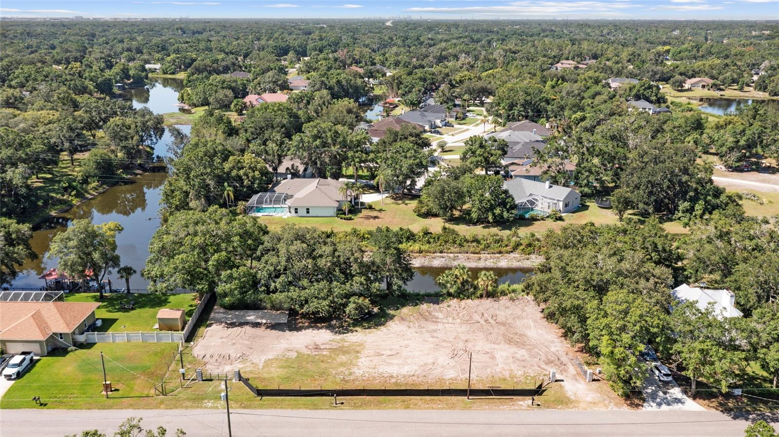Discover a rare opportunity to build your dream home on this beautiful 1.04-acre waterfront parcel at 5030 Duque Road in the heart of Lutz. Offering a prime setting with mature oak trees, scenic Tiffany Lake views, and the perfect blend of privacy, nature, and convenience, this unique property is ready for its next owner to bring their vision to life. Nestled among established custom homes, this picturesque lot extends across the water with the canal wrapping the property to create a panoramic backdrop and exceptional privacy for your future home. It’s a setting that is genuinely hard to find.
What sets this property apart is that the extensive due diligence and permitting work has already been completed. The parcel has been officially certified, with updated surveys and environmental documentation already in place. The current owners have successfully navigated the county approval process and even obtained a building permit before deciding to pursue other plans — significantly simplifying the path for a new owner looking to build.
A cleared homesite area prepared for construction, with a well and temporary power installed.  Combined with the completed certification and permitting work, these improvements provide a valuable head start and make this one of the most build-ready lakeside parcels available in the area.
Zoned RSC-2, the property offers the potential for a custom primary residence plus a secondary dwelling with living quarters up to 900 square feet, providing added flexibility for guests, extended family, or a home office, subject to county approval and setback requirements.
Conveniently located in desirable Lutz, the property offers easy access to I-275, US-41 (Land O' Lakes Boulevard), SR-54, and Dale Mabry Highway, providing quick connections to Tampa, Wesley Chapel, Land O' Lakes, and the greater Tampa Bay area. Shopping, dining, medical facilities, and hospitals are all nearby, while still maintaining the quiet feel of country living.
Imagine waking up to sunrise over Tiffany Lake from a home built exactly the way you've always envisioned it. Whether you're planning a luxury lakefront estate, a private retreat, or your forever home, this parcel offers a rare combination of natural beauty and development readiness.
Don't miss this rare chance to own one of the few remaining buildable waterfront parcels in one of Lutz's most sought-after locations. Schedule a visit today and start planning your dream home!
**The seller is in the process of removing personal items and equipment from the property.**