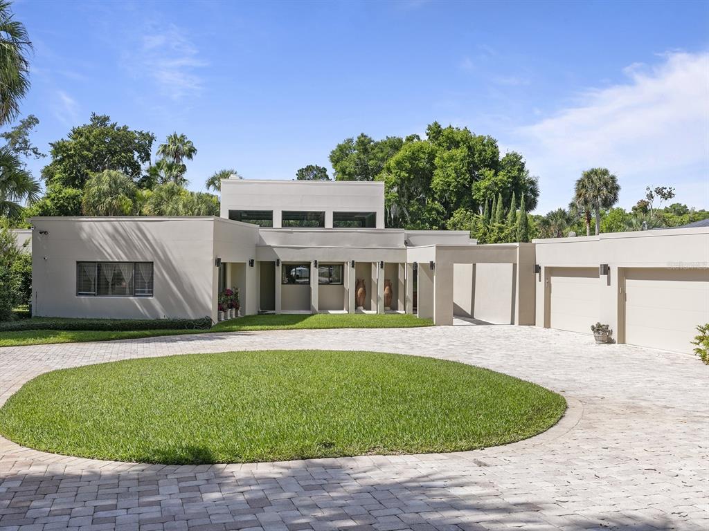 This spectacular contemporary, canal-front, home is perfect for those who appreciate the outdoors and enjoy boating on the Winter Park Chain of Lakes.  Gated and sited on one acre this beautiful home emphasizes entertaining indoors and outdoors, with a sense of harmony and relaxation throughout.  Discover a sweeping open floorplan with volume ceilings, amazing natural light, a custom-built wine cellar, and a formal dining room. Enjoy the beautiful gourmet kitchen with custom cabinetry, top-of-the-line appliances, and a gas range, all while overlooking a spacious family room. The oversized family living area features clerestory windows, built-ins, and lovely ceiling detail opening naturally to the gorgeous outdoor area.  The sparkling pool and stunning mature landscaping lead to the separate studio and covered boat dock, ready for quick access to Lake Maitland.  The private owner's areas feature a large bedroom, a lovely bath with a garden tub and shower, and huge walk-in closets.  Owners enjoy the private workout room and access to the outdoors.  The well-equipped office is set apart and perfect for quiet reflection.  The separate guest house is a great spot for visiting friends and family.  Two laundry rooms, large secondary bedrooms, a library, an four-car garage, and much more.  New roof and freshly painted exterior.
