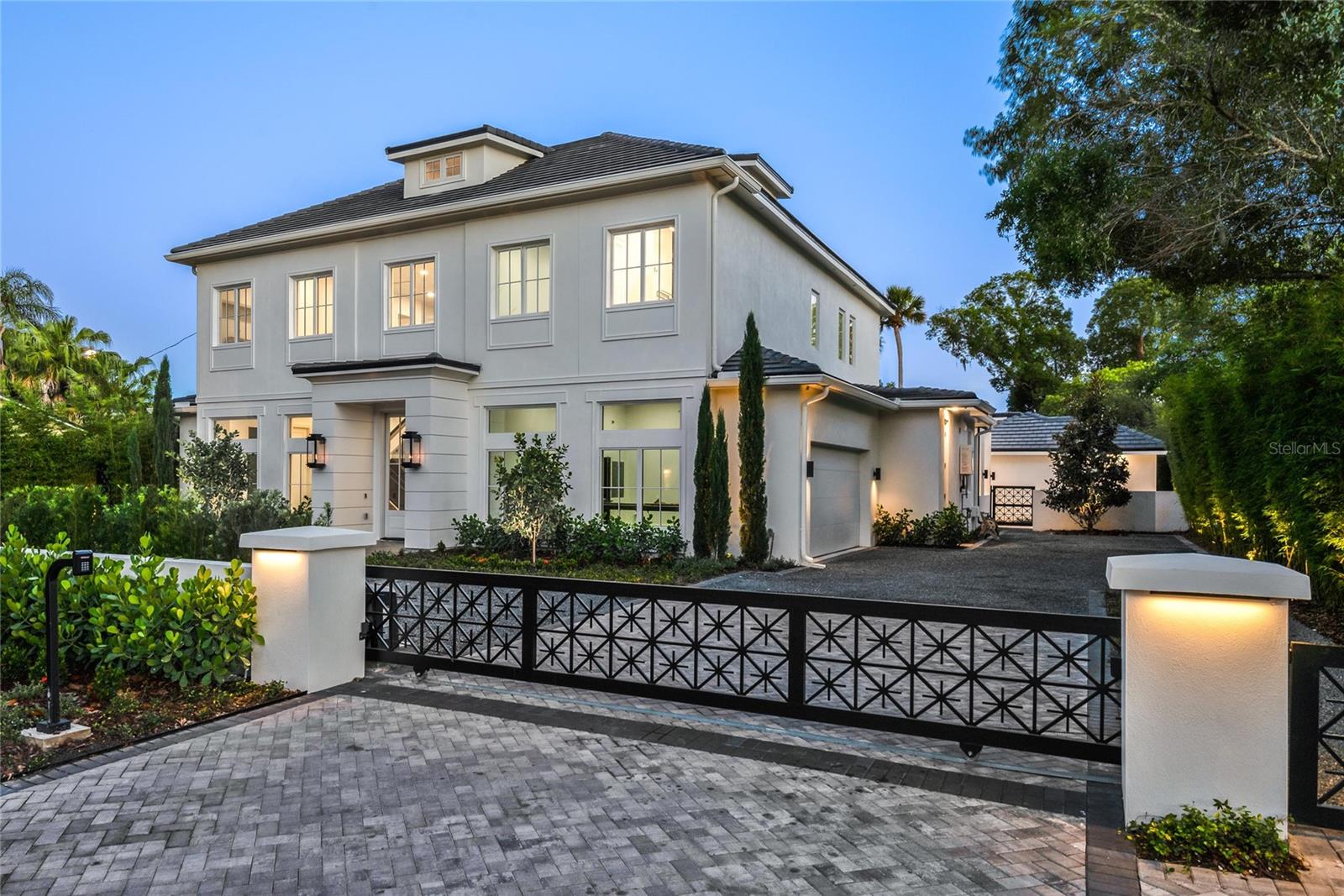 Under contract-accepting backup offers. New Hamptons-style residence offering a seamless blend of elegance and modern sophistication. A gated entrance opening to a circular driveway and motor court, set the stage for enjoying this exceptional estate.  As you enter home, an impressive 2-story foyer with a glass-paneled staircase wraps around a temperature-controlled wine room and a transparent glass elevator, effortlessly connecting all levels including an expansive third-floor multi-purpose space. Designed for contemporary living, the thoughtfully curated floor plan features a spacious open concept kitchen/gathering room along with the dining area enjoy a wall of glass doors and picture window overlooking an expansive lanai, and serene backyard with a sparkling pool and spa. The main residence offers 4 bedrooms, private home office, and multiple flex spaces, complemented by a detached pool cabana that serves as a 5th guest retreat or versatile use building. The gourmet kitchen is an entertainer’s dream, featuring dual 10-foot stone islands, a 60-inch Wolf range, dual 36-inch Sub-Zero refrigerator and freezer columns, a warming drawer, beverage center and a 146-bottle Sub-Zero dual-zone wine cooler. A separate pantry kitchen is equipped with a Dacor induction cooktop, convection oven, additional refrigerator, microwave, dishwasher and ample cabinetry, ideal for catering and meal preparation. The 1st-level primary suite is a tranquil retreat, offering a sitting area, an all-marble bath with a glass-enclosed shower, multiple body sprays, a soaking tub, and French doors leading to a secluded Zen garden with an outdoor shower and fountain. There is also a hidden private home office near the front of home. The second level hosts 3 additional en-suite bedrooms, a generous lounge area, bar, and a well-appointed laundry room with extra storage cabinetry.  As noted previously, there is also a unique 3rd level accessible by a staircase or elevator, that offers nearly 770 square feet of multi-use space. The outdoor living is elevated with a spacious lanai featuring motorized screens, a gas fireplace, dining space, and a summer kitchen with a 54-inch Coyote wood and gas grill, plus a separate burner beneath a remote-controlled louvered roof. There is also a detached cabana perfectly suited for a guest suite, fitness studio, additional office or game room, complete with a full bath, mini kitchen, and washer/dryer. Crafted with meticulous attention to detail, this home showcases Anderson windows, 10-foot solid doors, high-end lighting, plumbing and electrical fixtures, custom cabinetry built-ins, as well as Trane HVAC systems, ensuring quality and comfort... Lush landscaping, including magnolia trees, bamboo and cypress, surrounds the property, creating a private sanctuary. An attached side-entry garage features a powered car lift providing space for up to three vehicles. Ideally near Interlachen Country Club, Winter Park Racquet Club, Phelps Park/YMCA, and renowned Park Avenue. Note: Partial staging by RH and the furniture package can be purchased separately...