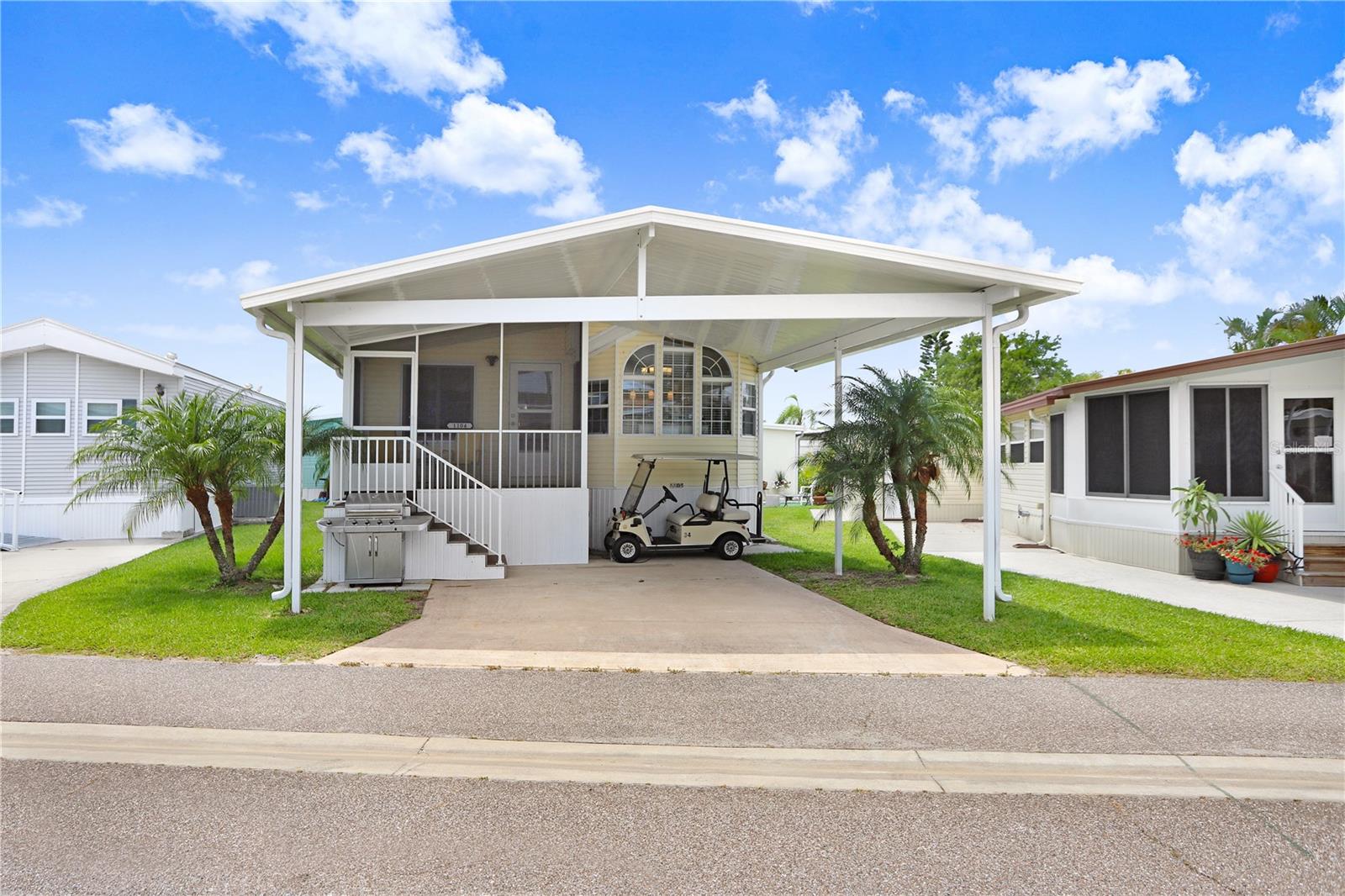 LOW HOA with NO LOT RENT! Fully Furnished Home with Golf Cart in Vibrant 55+ Community! This unique and charming 2-bedroom, 2-bath home with a versatile sleeping loft is being sold fully furnished—including a golf cart, all appliances, and even a grill—making it truly move-in ready! Relax on the screened front porch, the perfect spot for morning coffee or chatting with friends. Inside, enjoy the open feel created by vaulted ceilings, pendant lighting over the breakfast bar, and a spacious dining area. The living room features oversized, comfy chairs and a mounted TV. A sliding barn door leads to the primary suite, complete with two armoires, a second TV, and its own exterior door. Both bathrooms offer walk-in showers (no tubs), and the layout features multiple levels for added privacy and interest. The second bedroom, a few steps down, includes extra storage and a stacked washer/dryer unit. Upstairs, two loft areas with built-in storage provide additional sleeping or hobby space. Additional features include a carport, central A/C, concrete pads on both sides of the unit, and easy access to the crawl space for bonus storage. Located in the desirable Sugar Creek Country Club, where low quarterly HOA fees of just $600 cover internet, cable, water, sewer, trash, and lawn care. Don't miss out on this fully furnished gem in an active and welcoming 55+ community!