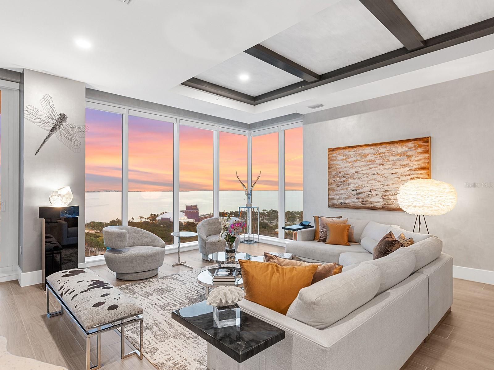One or more photo(s) has been virtually staged. Perched high above Sarasota Bay on the 15th floor, this exceptional residence is a refined expression of modern luxury, offering a seamless fusion of architectural elegance and breathtaking, ever-changing vistas. Walls of glass frame vibrant sunsets, the city skyline, and the tranquil beauty of the barrier islands, creating a daily backdrop that is both dynamic and serene. More than a residence, this home delivers an elevated lifestyle, combining the scale and privacy of a private estate with the effortless sophistication of luxury condominium living. A semi-private elevator opens directly to an elegant foyer, where hand-painted walls, bespoke lighting, and wood-look plank tile flooring introduce the home’s refined aesthetic. Beyond, the great room unfolds as a striking showcase of artistry and craftsmanship, defined by soaring coffered ceilings, a dramatic stone accent wall with a built-in fireplace, and floor-to-ceiling windows that extend seamlessly to a private balcony overlooking sweeping city and coastal views. Anchoring the living space, the chef’s kitchen is both an entertainer’s dream and a functional work of art. A quartz-topped island with integrated storage, seating, and beverage drawers serves as the centerpiece, complemented by custom cabinetry, a designer tile backsplash, and premium Sub-Zero and Thermador appliances, including a gas cooktop and double wall oven. A built-in bar with glass shelving and a beverage cooler adds an additional layer of sophistication for hosting and everyday enjoyment. The primary suite is a private sanctuary of exceptional serenity, featuring floor-to-ceiling windows, a private terrace, and two custom-designed walk-in closets. The spa-inspired bath is equally indulgent, offering a quartz vanity, a soaking tub, a walk-in glass shower, and expansive windows that bathe the space in natural light. Two additional guest suites, a dedicated workspace, and a thoughtfully designed laundry room with extensive cabinetry further enhance the home’s comfort and functionality. Three private terraces provide breathtaking vantage points with views extending to Siesta Key, Lido Key, and Longboat Key. Residents of BLVD Sarasota enjoy access to an unparalleled collection of world-class amenities, including a rooftop deck with a zero-horizon pool, a state-of-the-art fitness center, elegant club and wine rooms, a dog grooming salon and park, and an indoor golf simulator. BLVD Sarasota stands as a landmark of contemporary luxury, redefining high-rise living in the heart of downtown Sarasota.