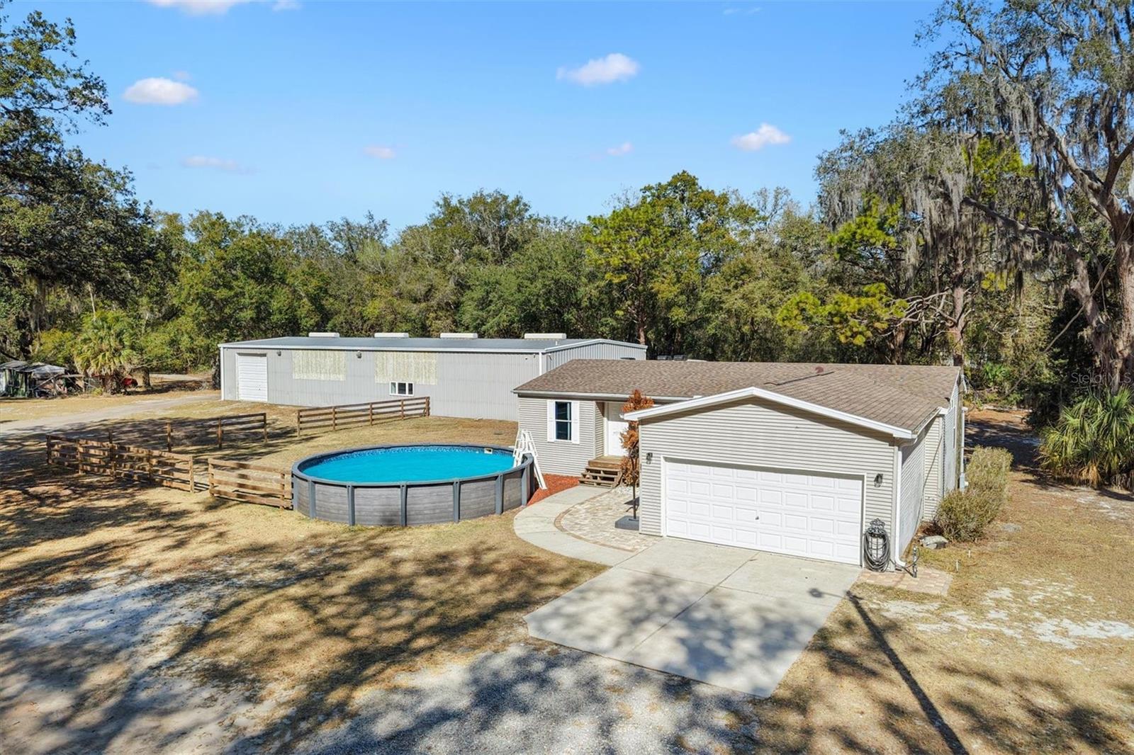 WOW -$$$ HUGE PRICE REDUCTION$$$ - LOOKING FOR A LARGE SPACE FOR YOUR HOME BUISNESS/ WORKSHOP/ HOBBIES, ETC. HERE IT IS, (42 x 100 ft.) 4200 sq ft metal storage building with 14 ft high ceilings with 3 large garage doors plus 3 offices with break room and 1/2 bath under heat and air. You can have your 3-bedroom home and Business/workshop/auto collection etc. Plenty of room to park a number of vehicles inside and outside on 1.1 acre, plus a well-appointed charming 3-bedroom home features an open floor plan with spilt bedrooms a large eat in kitchen with island and lots of counter and cabinets and walk through laundry room that leads to the 2 car 20x20 garage. large living room with slider to deck is light and bright with vaulted ceilings and split bedrooms. The large Primary bedroom with en-suite bath offers double vanity sinks and a walk-in shower and walk-in closet. Great opportunity for artist, collectors, hobbyist, or business opportunity ETC.  The 1.1 area is zoned Residential/agriculture off Micro Racetrack rd. and just a few minutes from 466A and the villages. House roof 2019 and HVAC 2018. Call for appointment.
