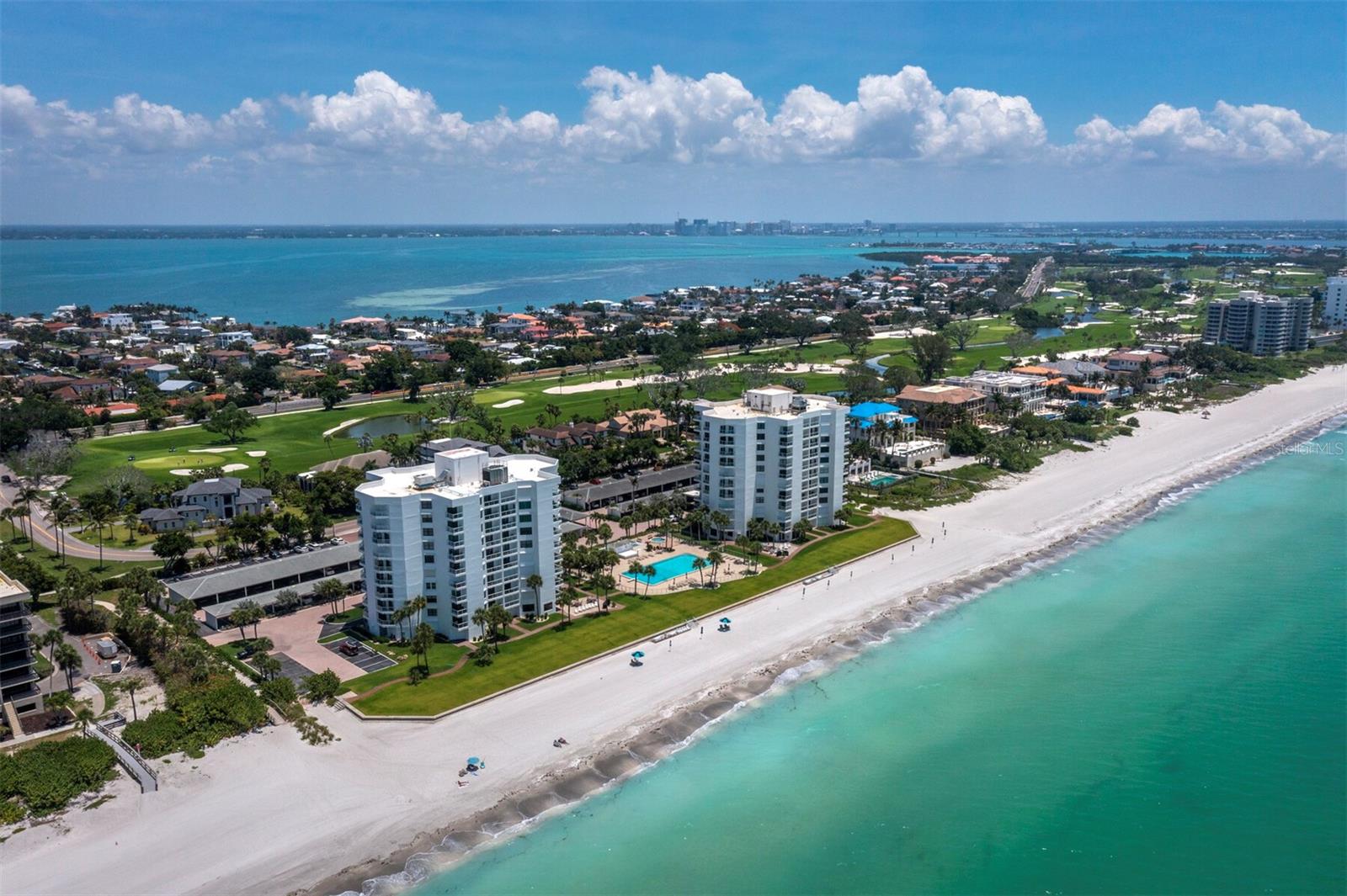Set on the 9th floor at Privateer North, behind the gates of the Longboat Key Club, this beautifully renovated corner residence blends sweeping views, refined finishes and effortless coastal living. Offered TURNKEY FURNISHED, the 2-bedroom, 2-bath home looks out across the golf course, Sarasota Bay, the Intracoastal Waterway and the downtown Sarasota skyline, creating a view that shifts beautifully from morning light to evening sparkle. Inside, the renovation is immediately apparent. Clean neutral finishes, recessed lighting, crisp white trim and an open, comfortable floor plan keep the focus on the scenery beyond the glass. All glass is high-impact, hurricane-rated, and the residence also includes hurricane shutters for added peace of mind. The kitchen is designed for both everyday living and easy entertaining, with quartz countertops, custom cabinetry, high-end appliances, a wine refrigerator and detailed tilework. An inviting eat-in area frames bay views, bringing the water into daily life. The living and dining areas open to a terrace overlooking manicured grounds, the golf course and the bay beyond. Both bedroom suites are generously sized with walk-in closets, and the primary suite enjoys its own private terrace. The updated baths feature tasteful finishes, including a beautifully tiled walk-in shower in the primary bath. Privateer North offers a true beachfront lifestyle with a secure lobby, on-site management, heated pool and spa, fitness center, tennis and pickleball courts, social spaces and private beach access. For those seeking an even broader resort experience, optional membership at the Longboat Key Club offers access to 45 holes of golf, the Tennis Gardens with 20 Har-Tru courts, private dining, beach and pool facilities, spa, fitness, wellness programming, social events and marina amenities. Located on the sought-after south end of Longboat Key, the residence is just minutes from St. Armands Circle, downtown Sarasota, fine dining, shopping, arts venues and the area’s best coastal amenities.