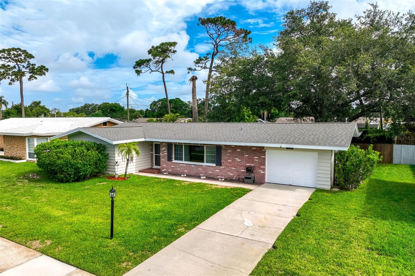 Nestled in the highly desirable Woodridge neighborhood of Clearwater, this beautifully maintained residence offers the perfect combination of location, comfort, and charm. Just 3 miles from the sugar-white sands of Clearwater Beach, Woodridge is known for its wide, sidewalk-lined streets, manicured homes, and the added benefit of no HOA fees.

This inviting 3 bedroom, 2 bathroom home features a desirable split floor plan and an expansive Florida room filled with natural light, creating the perfect space for relaxing, entertaining, or enjoying views of the picturesque backyard. The private, fenced outdoor setting is truly special, offering two patio areas, attractive stone accents, and a peaceful atmosphere surrounded by mature landscaping.

The updated kitchen is equipped with soft close cabinetry, stainless steel appliances, and a double oven, making meal preparation a pleasure. Throughout the home, you'll find a beautiful blend of engineered hardwood flooring and polished terrazzo, adding warmth, character, and timeless appeal.

Additional features include fresh interior and exterior paint, a whole house water filtration system, alarm system, oversized one car garage, and excellent curb appeal. Located outside of a flood zone, this property provides added peace of mind.

Ideally situated in the heart of Clearwater, you'll enjoy easy access to shopping, dining, parks, and major employment centers. Tampa International Airport is approximately 30 minutes away, vibrant downtown St. Petersburg is within a 30 minute drive, and the charming waterfront community of Dunedin is just minutes from your doorstep.

A rare opportunity to enjoy a quiet neighborhood setting while remaining close to everything Tampa Bay has to offer.