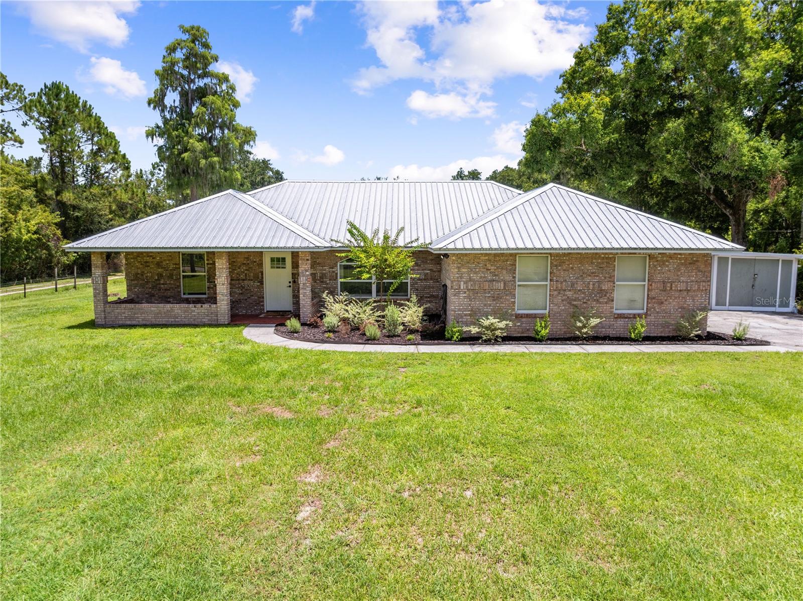 Welcome home to this beautifully updated 4-bedroom, 2-bathroom single-family home, perfectly situated on a spacious 1-acre lot with no HOA! Offering approximately 1,750 square feet of comfortable living space, this property combines modern updates with the freedom of country-style living. The heart of the home is the remodeled kitchen, featuring stainless steel appliances, a center island, and plenty of space for cooking, entertaining, and gathering with family and friends. Stylish updated flooring flows throughout the entire home, creating a fresh, cohesive feel. The guest bathroom has been tastefully remodeled, while the beautifully renovated primary bathroom showcases a new vanity and a stunning walk-in shower, providing a private retreat at the end of the day. Outside, you'll appreciate the durability of the metal roof and the expansive one-acre homesite, offering endless possibilities for gardening, outdoor activities, or storing your boats, RVs, and recreational toys. Located on a newly paved road with no HOA restrictions, you'll enjoy both convenience and flexibility. Ideally located just a short drive from Florida's beautiful beaches, Orlando International Airport (OIA), shopping, dining, and major attractions, this move-in-ready home offers the perfect blend of peaceful living and everyday convenience. Don't miss your opportunity to make this exceptional property your own!