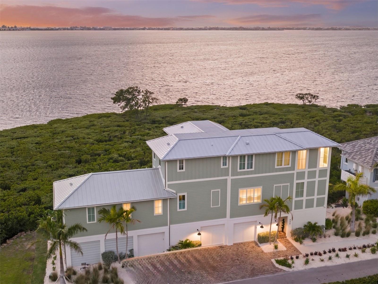 RARE LUXURY WATERFRONT OPPORTUNITY IN HARBOUR ISLE! Enjoy unobstructed, panoramic views of Anna Maria Island and Tampa Bay from this recently completed (2024) luxury waterfront home. Perfectly positioned within the master-planned community of Harbour Isle, this three-level coastal retreat blends modern elegance with breathtaking scenery—offering a front-row seat to spectacular sunsets and frequent dolphin sightings.
An elevated pool and outdoor kitchen overlook the tranquil waters of Anna Maria Sound, delivering an exceptional indoor-outdoor living experience. Every detail reflects superior craftsmanship, from architectural precision and custom millwork to designer finishes, premium appliances, and bespoke cabinetry.
A spacious multi-car garage offers room for three vehicles plus a golf cart, enhanced by a converted storage area to a third-car garage, overhead storage, air conditioning in both the garage and gym area, and a fenced and turfed space behind the garage with added access door (in process). The extended paver driveway accommodates up to three vehicles with ease.
The home is further upgraded with a whole-home generator, remote-controlled window shades, mounted TVs with in-wall electrical, and thoughtful modern conveniences throughout.
The main living area is easily accessed via a private elevator or a sunlit staircase with scenic views. The expansive great room and chef’s kitchen are designed to maximize sweeping water views, while the primary suite offers a serene retreat with a spa-inspired bath, soaking tub, and generous walk-in closet. Open-concept living and dining areas flow seamlessly to a large outdoor entertaining space overlooking the water.
The upper level includes a luxurious junior suite and two additional guest bedrooms, each with ensuite baths and abundant closet space. A versatile bonus area provides flexibility for a media room, office, or wellness space.
Located within the highly sought-after Harbour Isle community, residents enjoy exclusive access to a private clubhouse featuring a resort-style pool, state-of-the-art fitness center, Sky Bar & Restaurant, jacuzzi, private beach, and outdoor pavilion. Additional amenities include miles of walking and biking trails, kayak launches, multiple pools, and scenic gathering spaces.
Just minutes from Anna Maria Island’s renowned beaches and a short ride to Robinson Preserve’s nature trails, this home offers both tranquility and convenience. Nearby airports in Sarasota and Tampa/St. Petersburg provide easy access for travel. This is a rare opportunity to own a truly exceptional coastal residence in one of Florida’s most desirable waterfront settings.