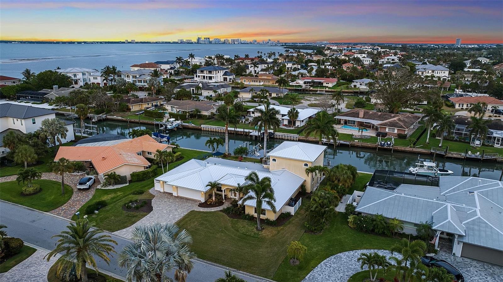 Tucked along one of the most sought-after canals in Country Club Shores, 524 Hornblower Lane is a waterfront residence that fully embodies the Longboat Key lifestyle, where boating access, beach proximity, and refined coastal living intersect with intention. Set on a 0.28-acre canal-front homesite with 107 feet of water frontage, the property offers what experienced boaters immediately recognize as premier water: wide, deep canals with quick, unobstructed access to Sarasota Bay and the Intracoastal. A composite dock, dual boat lifts accommodating vessels up to approximately 38 feet, and a dedicated jet ski lift create a true boating compound, designed for both serious use and effortless enjoyment. Behind its stately, columned façade, the residence spans over 3,000 square feet of living space, thoughtfully updated over time with an effective build year of 2005 and continued improvements, including impact-rated glass, a newer metal roof (2025), and recently replaced mechanical systems. The layout is both functional and flexible, with three bedrooms, three full baths, and a half bath arranged across a two-story design that balances everyday livability with elevated entertaining. The main living areas unfold with a coastal-modern sensibility, wood flooring, crown molding, and expansive sliders that frame views of the pool, lanai, and canal beyond. The kitchen, finished in a soft seafoam palette, blends custom shaker cabinetry, quartz surfaces, and professional-grade KitchenAid appliances with a dedicated beverage station, creating a space that feels equally suited for quiet mornings or hosting at scale. A standout feature of the home is its full entertainment space; an expansive theater and bar lounge designed as a destination in itself. With a projector system, surround sound, custom wet bar, and multiple gathering zones, it introduces a layer of lifestyle rarely found in properties of this scale. A cylindrical tube elevator provides a striking architectural moment while connecting this space directly to the private primary suite above. Upstairs, the primary suite is positioned to take full advantage of the waterfront setting, with a private balcony overlooking the canal, an oversized walk-in closet, and a spa-like bath complete with a jetted soaking tub, dual vanities, and a glass-enclosed shower with dual heads. Outdoors, the experience is equally intentional. A resort-style saltwater pool and spa anchor multiple seating and entertaining areas, complemented by an outdoor kitchen and low-maintenance landscaping that keeps the focus on the water. What elevates 524 Hornblower beyond its physical attributes is its location within the broader context of Longboat Key. Deeded beach access provides a direct connection to the Gulf, while proximity to St. Armand's Circle and the St. Regis Longboat Key Resort places world-class dining, shopping, and amenities just minutes away. The result is a rare dual lifestyle, boating on one side, beach on the other, anchored by one of the island’s most established and desirable neighborhoods. At its core, this is a property defined by access: to water, to the Gulf, to the lifestyle that has long made Longboat Key one of Florida’s most enduring coastal addresses.