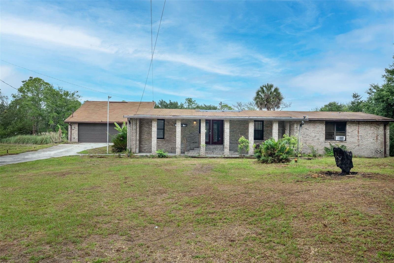 Canal-front home on Black Hammock Island situated on a quiet and secluded 1.13-acre lot featuring a sizable pond and scenic water views. Originally a manufactured home, the residence has been bricked in and expanded with a substantial addition featuring its own private entrance, and is now classified as a single-family home. This spacious property offers a large primary suite, a private in-law suite, and three additional guest bedrooms with a shared bathroom, making it ideal for multigenerational living. Enjoy outdoor living with a covered front porch and a side covered porch connecting the main house to the oversized detached garage of nearly 1,000 sq ft. The detached garage was originally designed as a 3.5-car tandem garage, with one bay converted into additional living space that can be used as a flex room and features its own window unit. The garage still offers ample storage space, currently utilized as a laundry room, along with attic storage and an upper-level patio and a large deck overlooking peaceful views. A large deck attached to the garage overlooks the canal and pond, providing the perfect setting for entertaining or relaxing in a peaceful, tranquil environment. The property is in need of repairs and updates and is being sold as-is.