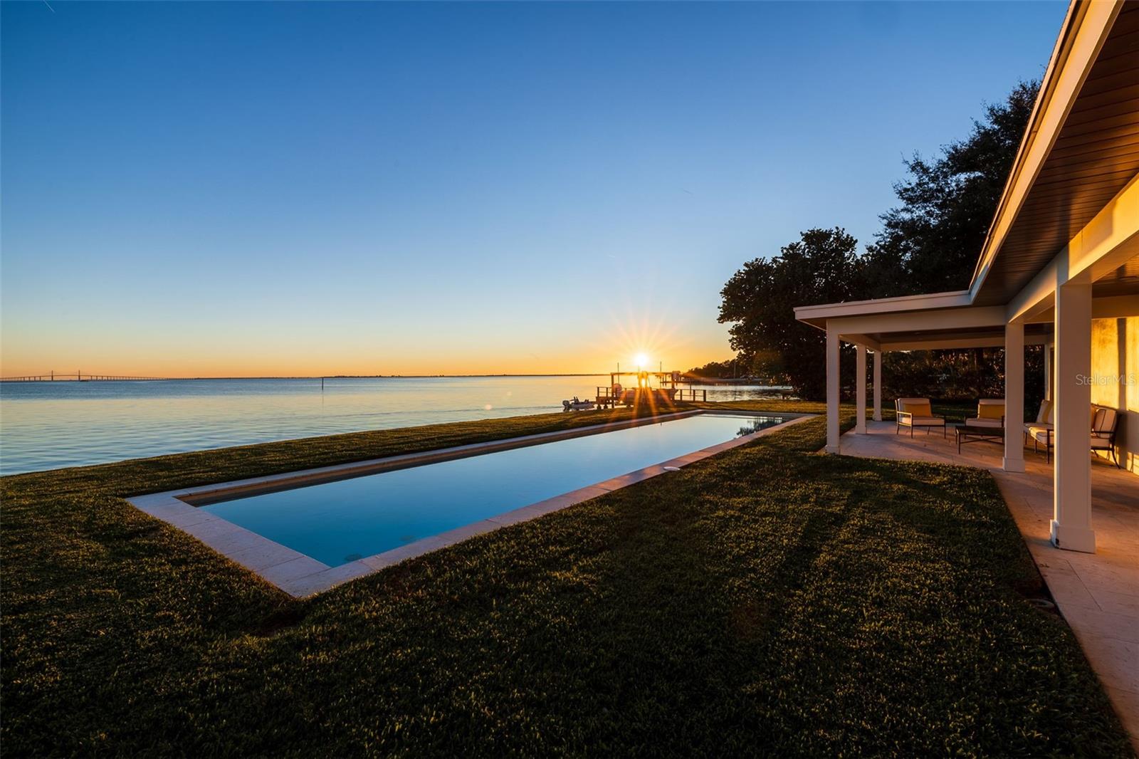 Under contract-accepting backup offers. GATED HOME WITH 175’ OF OPEN TAMPA BAY WATERFRONT (NO BRIDGES) IN QUIET COLONY POINT WITH SUNRISE-TO-SUNSET VIEWS, DOCK, LIFT, POOL & SPA ON A PRIVATE .36 ACRE LOT. Located at the end of a quiet cul-de-sac within the Colony Point enclave of Pinellas Point, this gated waterfront home offers 3,278 sq ft, 4 bedrooms, and 3 bathrooms with expansive open-bay views and minimal through traffic. The property features 175 feet of direct Tampa Bay frontage, unobstructed sight lines to the Sunshine Skyway, and immediate boating access with no bridge restrictions. Designed for a functional waterfront lifestyle, the property includes a new seawall (2024), composite dock with water and electric (2020), and a 10,000 lb boat lift, providing reliable access for daily boating. The .36-acre lot with no HOA or deed restrictions offers flexibility and privacy rarely found in this location.
The interior layout is oriented to capture water views from nearly every room. The kitchen was updated in 2019 and includes a Sub-Zero refrigerator, Wolf gas range, dual pantries, and generous storage, connecting naturally to the main living areas. The primary suite is located upstairs with direct access to a rooftop terrace overlooking Tampa Bay, creating an additional outdoor living space. Interior features also include a wood-burning fireplace and a dedicated laundry room with storage and utility sink.
Outdoor living is centered around a 52’ saltwater pool with heated spa, covered lanai, and open backyard leading to the water, designed for both everyday use and entertaining. Recent updates include a tile roof (2021), HVAC (2021), electrical upgrades (2019), and impact-rated windows and doors installed between 2022–2025, supporting long-term durability and insurability. Colony Point is a well-established waterfront neighborhood known for privacy, mature landscaping, and low-traffic streets, while also benefiting from a rapidly growing surrounding area. Within approximately 10 minutes, you’ll find Publix, Sprouts Farmers Market, Starbucks, and Maximo Marina, along with additional dining and everyday conveniences—bringing modern accessibility to this waterfront setting. The home is also just minutes from I-275, providing efficient access to downtown St. Petersburg, Tampa, Sarasota, and the Gulf beaches. This property offers a combination of open-bay frontage, lot size, gated privacy, and boating capability that is increasingly limited in the St. Petersburg waterfront market.