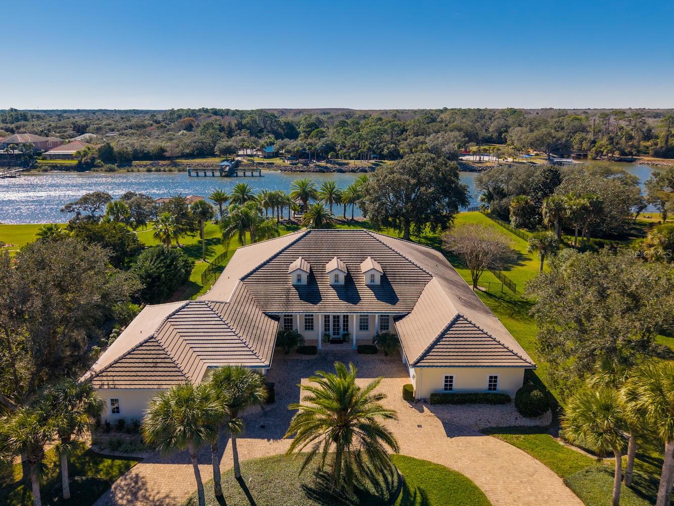 Exquisite Intracoastal Waterfront Estate in Hammock Dunes – Island Estates
Discover unparalleled coastal luxury in this meticulously crafted waterfront home, built with the highest-quality materials and finishes. Expansive walls of glass and French doors capture stunning panoramic views of the Intracoastal Waterway, bathing the interiors in natural light while creating effortless indoor-outdoor transitions.
Enter through a grand foyer featuring elegant tongue-and-groove ceiling details, leading to a soaring great room, formal dining area, and gourmet chef's kitchen. The kitchen boasts premium stainless steel appliances, custom cabinetry, a spacious center island with breakfast bar, glass-front butler's pantry, and a large walk-in pantry.
Unwind on the generous covered lanai, overlooking a sparkling pool, lush tropical landscaping with mature palms, and spectacular sunsets across the Intracoastal. Ideal for outdoor entertaining, al fresco dining, or relaxed lounging. The property includes a covered boat dock with a 6,000 lb lift, water, and power.
Situated on a premium wide estate lot with approximately 194 feet of direct Intracoastal frontage. Elevated at ~19 ft FFE in an X flood zone for enhanced security and peace of mind.
The serene primary suite offers a private retreat with water views, ample space, and a luxurious spa-inspired bath complete with soaking tub, oversized walk-in shower, and dual vanities. A dedicated home office with direct outdoor access provides a productive and inspiring environment. Additional spacious guest bedrooms and baths ensure comfort and privacy for family and guests.
Brand New in 2025: A beautiful 570 sq ft guest/mother-in-law suite with private entrance, 116 sq ft covered patio, and direct Intracoastal views. This versatile addition features a living area, kitchenette, bedroom, full bath with large walk-in closet, and stacked washer/dryer – perfect for multi-generational living or extended visitors.
Nestled on quiet, tree-lined Capri Court – an exclusive cul-de-sac of just nine custom estates – within the prestigious gated Island Estates neighborhood of Hammock Dunes, Palm Coast. Private community beach access to the Atlantic Ocean is just minutes away.
Optional membership available to the renowned Hammock Dunes Club, celebrated as one of the world's top private clubs. Enjoy two Audubon-certified golf courses, oceanfront clubhouse, resort-style pool, 5,000 sq ft fitness center, croquet, and abundant social activities. Exceptional dining options include elegant oceanfront dining, casual tavern fare, alfresco experiences, and Low Country-inspired cuisine – all embodying the finest in Florida coastal living, golf, boating, and leisure.
This exceptional waterfront masterpiece offers refined luxury where every detail evokes a perpetual vacation in paradise. Schedule your private showing today!