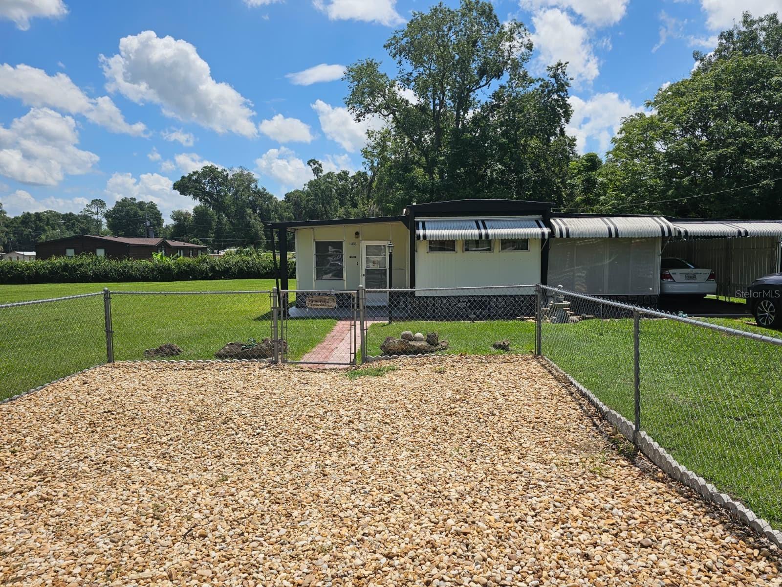 Welcome to Breezewood Subdivision in Summerfield, conveniently located between Belleview and The Villages. Enjoy the nearby shopping, dining, entertainment, and amenities of The Villages without the burden of HOA fees.

This furnished one-bedroom, one-bath home began as a single-wide and has been thoughtfully expanded over the years to create an inviting and spacious layout. The kitchen is equipped with a gas cooktop, wall oven, and refrigerator, making meal preparation convenient and efficient. Adjacent to the kitchen is a dining area with seating for four, featuring built-in cabinets that provide additional storage while creating a charming separation from the home's original living room.

Beyond the original living space, you'll find a large living room, a versatile den that can easily serve as an office or additional sleeping area, and a bright Florida room filled with natural light from its many windows.

Outside, the home features a covered carport with a storage shed, as well as a spacious covered back porch just off the Florida room, providing the perfect space to relax or entertain.

Situated on a generous 0.69-acre lot, the fully fenced and cleared yard offers endless possibilities. There's plenty of room for boats, RVs, trailers, recreational vehicles, or animals, along with an additional detached shed for even more storage.

Whether you're looking for a full-time residence, a seasonal getaway, or an investment opportunity, this charming property combines comfort, space, and an unbeatable location.