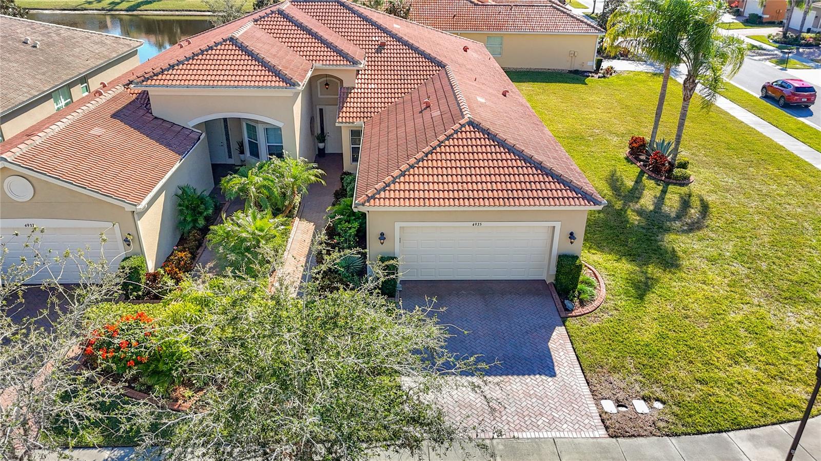 Located in one of the newest sections of Valencia Lakes, this exceptional home offers the perfect blend of luxury, comfort and carefree Florida living. Situated on an oversized corner lot, it enjoys a scenic water outlook, a private backyard and beautifully manicured landscaping enhanced by decorative concrete borders and professionally installed landscape lighting. Built just a few years ago as a GL Homes designer spec home, this residence showcases numerous builder upgrades and -  added later - additional premium investments done by the owners, creating a truly first-class home. Inside, you'll find a bright, open split-bedroom floor plan with soaring 9-foot ceilings. Elegant diagonal 18"x18" Travertino ceramic tile flows throughout the main living areas and den/third bdrm, while the primary and second bdrms feature plush carpeting. Extensive crown molding, custom wainscoting, chair rails and decorative mirror framing in the dining room add timeless sophistication rarely found in comparable homes. Gourmet kitchen features quartz countertops, a high-quality tumbled stone backsplash and an extended raised breakfast bar offering additional seating. Premium GE stainless steel appliances include a range, microwave, French-door refrigerator and newer LG dishwasher. Beautiful 42-inch maple pecan cabinetry offers crown molding, under/over cabinet lighting, soft-close drawers with undermount glides, and a custom pantry with rollout shelves. Culligan water filtration system completes the kitchen, while the spacious breakfast nook provides the perfect spot for casual dining. Spacious primary suite features a large custom walk-in closet and elegant ensuite bath with dual vanities, maple cabinetry, quartz countertops, undermount sinks, beautifully tiled walk-in shower extending to the ceiling with decorative glass listello accents and a built-in corner bench. Guest bath also features an upgraded quartz countertop with an elegant banjo-style extension. Currently used as a home office, the third bdrm includes professionally designed custom built-in cabinetry with a desk, file storage and bookshelves, creating an ideal workspace. Expansive living room opens through triple 8-foot sliding glass doors to a screened lanai with extended pavers, where you'll enjoy peaceful water views and exceptional backyard privacy. Additional upgrades include: LG front-loading washer/dryer with utility sink, upgraded lighting, ceiling fans throughout, additional recessed lighting in living room, primary bdrm, office and lanai, water softener system, hurricane shutters, epoxy-coated garage floor, expertly maintained HVAC system. Valencia Lakes is one of the area's premier 55+ active adult, golf cart-friendly communities, offering resortstyle amenities with a spectacular 40-acre waterfront recreation area, heated resort pool, lap and resistance pools, 40,000 sqft clubhouse, fitness center, tennis, pickleball, bocce, basketball, dog park, baseball park, community garden, RV and boat storage, a wide variety of clubs and social activities, deluxe bistro led by Chef Paul Mattison. More than 100 acres of nature preserves provide beautiful walking and biking paths, peaceful water views, and abundant wildlife. Conveniently located just 30 to 45 minutes from Tampa, St. Petersburg, and Sarasota, and close to shopping, dining, medical facilities, golf courses, and Tampa International Airport, this exceptional home offers the perfect combination of luxury, location, and lifestyle.