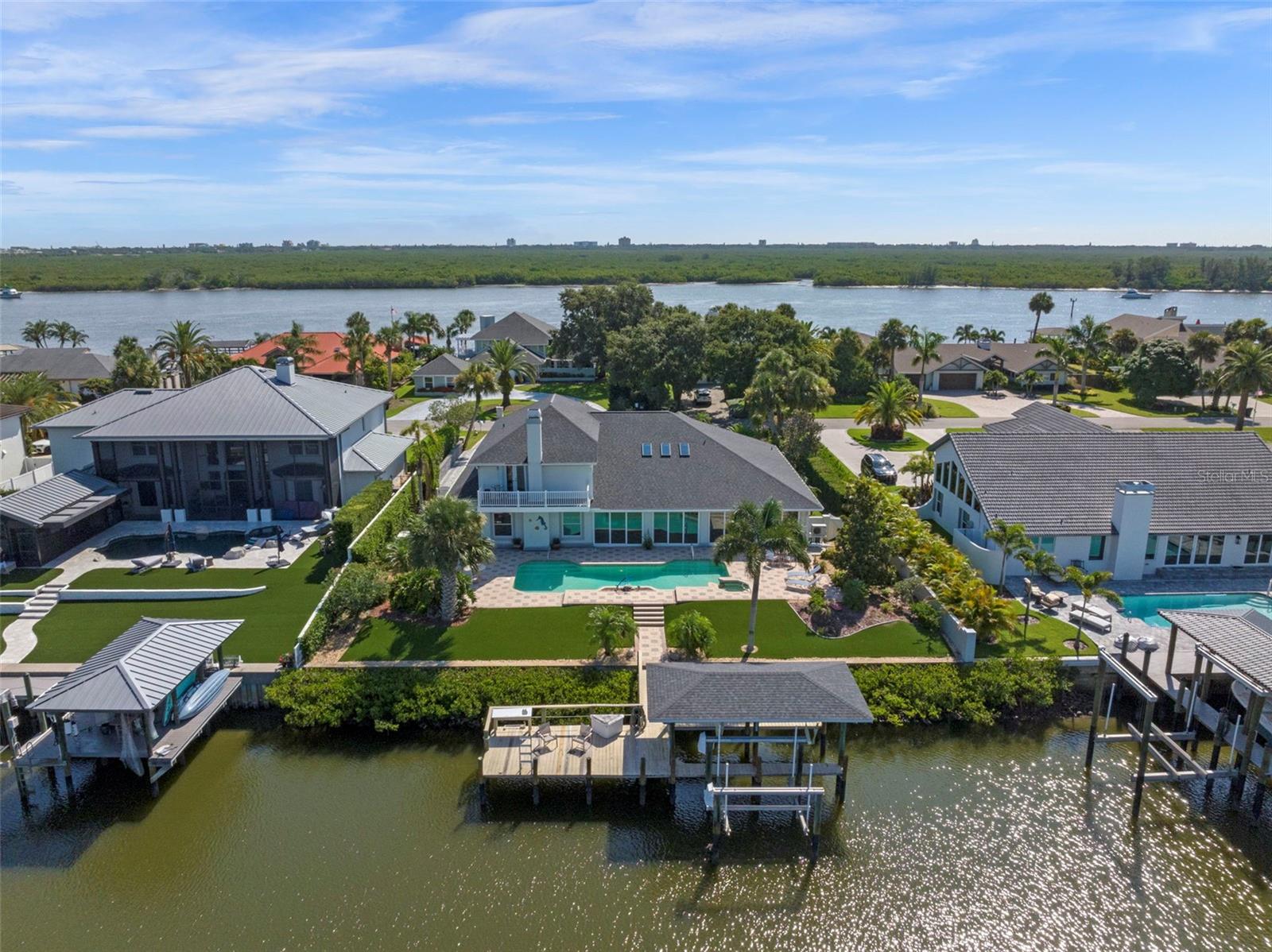 Discover a rare opportunity to own a CUSTOM-RENOVATED luxury WATERFRONT home in the exclusive Yacht Club Island Estates with EASY OWNER FINANCING AVAILABLE AT 4.99% WITH 25% DOWN.—the only gated Intracoastal Waterway community in New Smyrna Beach offering direct deep-water access. Available for the first time in over 25 years, this meticulously maintained coastal estate is a true waterfront treasure, showcasing panoramic views of the Indian River and featuring a private two-slip dock, lifts and station to clean your catch-of-the-day. Nestled within an intimate gated enclave of just 23 homes, this property blends timeless design with modern upgrades in one of Florida’s most coveted fishing and boating communities. The residence offers 4,281 square feet of refined interior space (5,180 total square feet under roof), including 4 bedrooms, 4.5 bathrooms, and flexibility for a secondary primary suite on the main level—ideal for multi-generational living. From the smooth stucco exterior and brick paved driveway to mature landscaping and private courtyard entry, every detail of this home reflects high-end coastal living. Inside, the open-concept layout features 10-foot ceilings and uninterrupted sightlines of the waterway, beginning with a formal living and dining space that flows seamlessly to the spacious family room anchored by a stunning coquina stone gas fireplace with river views to soothe the soul. The remodeled chef’s kitchen serves as the heart of the home, featuring new custom cabinetry, granite countertops, designer lighting, premium appliances, wine fridge, breakfast bar, and a bright breakfast nook. The expansive primary suite offers French doors opening to the sunroom and out to the pool area.  Dual walk-in closets, and a spa-inspired ensuite with double vanities, a jetted soaking tub, and a walk-in shower. Upstairs, three additional bedrooms and two bathrooms are complemented by a private balcony overlooking the Intracoastal Waterway. Ideal for entertaining, the 35-foot Florida sunroom features an artist-designed custom bar with a wet sink which opens to an outdoor oasis with new sliding glass doors, a resort-style "volleyball" pool, and a waterfall cascading from the spa. The fully fenced, low-maintenance backyard leads directly to the dock, enhanced by water-to-dock vinyl-wrapped pilings for lasting durability. Additional features include NEW HVAC systems, Anderson Renewal energy-efficient windows, a Generac whole-home generator and central vacuum, interior laundry room, walk-in pantry, and an oversized 3-car garage. This exceptional waterfront property combines luxury, comfort, and functionality in a prime New Smyrna Beach location near the Yacht Club, Historic Canal Street, Flagler Avenue, premier golf courses, and the beautiful sand beaches of the Atlantic Ocean.  From sunrise to sunset, this home offers a front-row seat to the natural beauty of coastal living—Don’t miss your opportunity to own this one-of-a-kind waterfront home at 1216 Commodore Drive—schedule your private showing today and experience the very essence of Florida and life on the water.