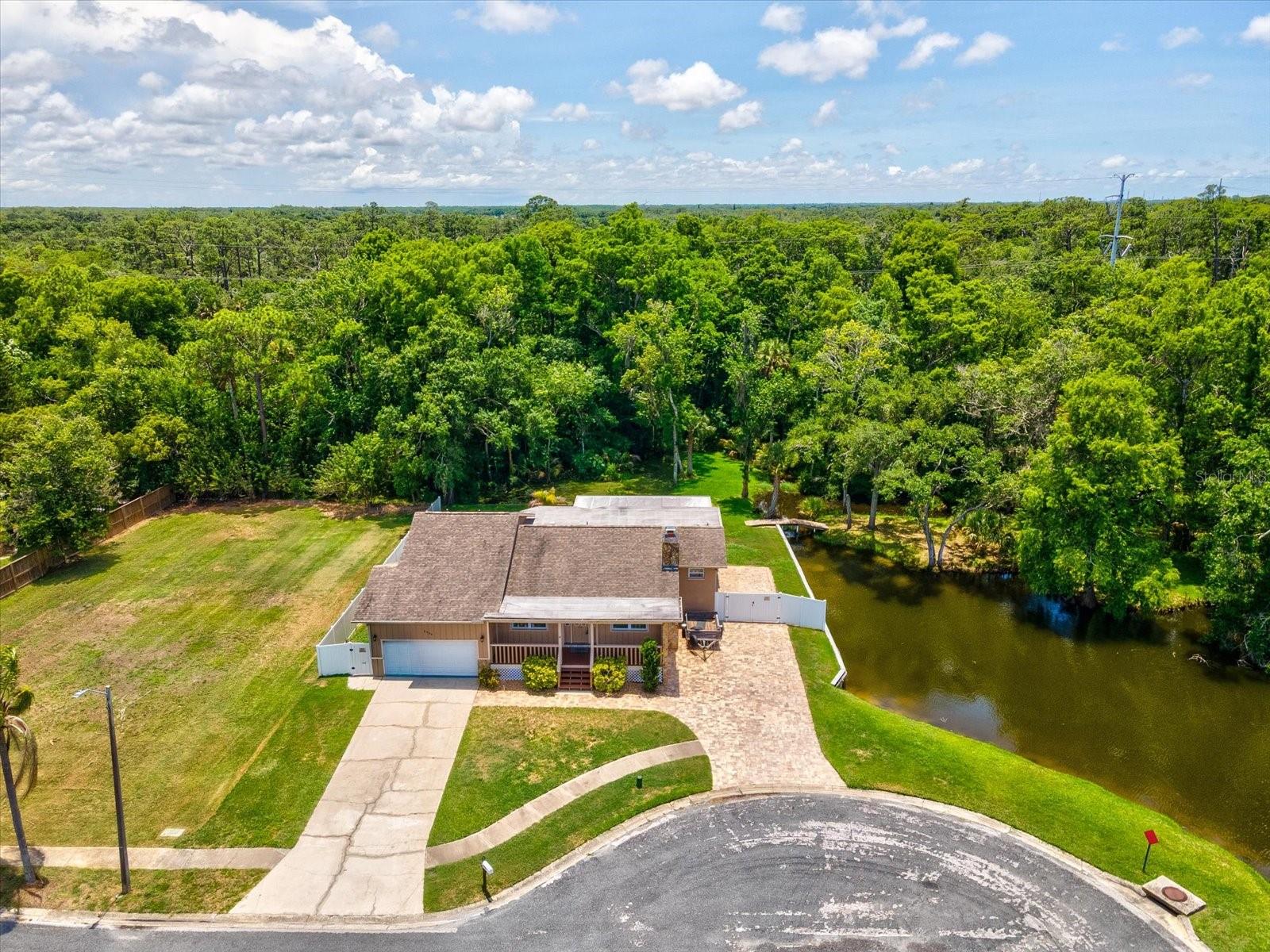 Welcome to this one-of-a-kind Holiday retreat on 0.74 acres, where a private park-like setting, tranquil pond views, wildlife in your backyard and thoughtful interior features create a truly special place to call home. Nestled among mature trees, this property offers a peaceful setting rarely found in today's market. Inside, you'll find all tile flooring throughout and a warm, inviting living area highlighted by a stone veneer fireplace, perfect for relaxing evenings at home. A versatile recreation room currently serves as a family room and office, providing flexible space to fit your lifestyle. Designed with both function and style in mind, the kitchen features granite countertops, abundant cabinet space, modern appliances, a double oven, and an island-mounted electric cooktop with exhaust. Whether preparing everyday meals or entertaining guests, this kitchen is ready to meet your needs. The natural beauty of this property truly sets it apart. Front and rear covered porches overlook the picturesque pond and surrounding landscape, creating the perfect places to enjoy morning coffee or unwind at the end of the day. A charming bridge crosses a small stream, while the firepit area offers a peaceful gathering spot surrounded by nature. Located in Holiday, this home offers convenient access to the Tampa Bay area while maintaining a quieter, more affordable lifestyle. Enjoy nearby parks, nature preserves, boating, fishing, waterfront dining, and outdoor recreation, including Anclote River Park and Key Vista Nature Park. The home is located in FEMA Zone AE; however, the owner states that the property has never flooded. With pond views, mature landscaping, covered porches, a fireplace, flexible living space, and a truly unique natural setting, this property offers privacy, comfort, and a lifestyle that is difficult to find. Schedule your private showing today.