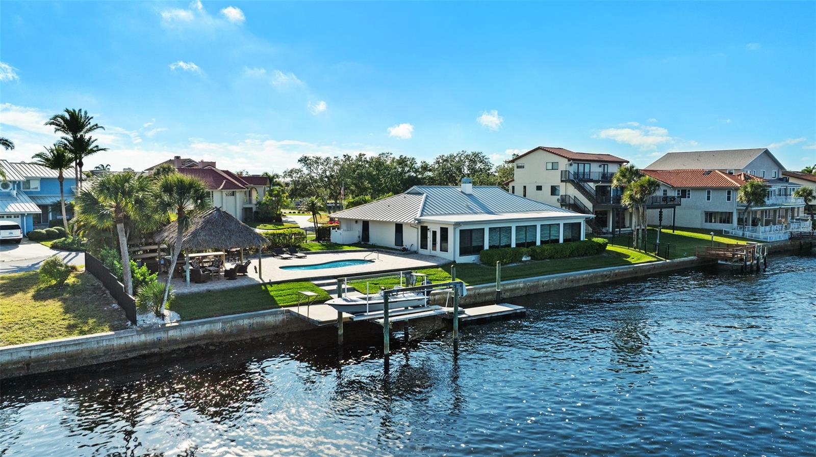 This Single-Story WATERFRONT Home Sits on an Oversize Lot with 150 feet of Water Frontage with 180 degrees BREATHTAKING VIEWS of the Gulf of Mexico from Sunrise to Sunsets and Nights with Full Moon. Welcome Home to this POOL Home with 5 Bedrooms, 3 Bathrooms and a 2-Car Garage PLUS a DOCK with Electric and a 12,000 lb. BOAT LIFT. From there you have a HUGE Pool Deck with a Custom Tiki Hut made with Brazilian Ipe Wood for durability that includes outdoor Grilling Area with both a Gas Grill and Green Egg ~ Ready for anything from a Bar-BQ to pool parties or Lazy Days indulging in Vit-D Therapy! Whether Boating, Fishing or Paddle boarding this Home is Ready to Accommodate All Your Water/Outdoor Activities! PLUS, Access to the Private Beach Area with Pavilions whether a Relaxing Beach Day or Throwing a Celebration for Many!  Every Inch of this 3308 Heated Sq. Ft. Home was Beautifully Designed with Meticulous Attention to details from the Metal Roof with Hurricane Clips (Installed 2023) to the Cambria Quartz Countertops in the Kitchen. As you drive up to the home you are greeted with a driveway done with decorative pavers, walking up to the entrance you have Courtyard Sitting Area featuring a WATER FOUNTAIN. The Double Door Entry features Glass detailing with British Style Door Knobs. As you walk in the home has a Split Style open floor-plan to allow water views from all the Hurricane Impact Windows Surrounding the front of the home from multiple areas in the home especially from the heart of the home ~ the Kitchen. No expense was spared with the kitchen remodel to make it a Chef’s dream ~ from the spacious Cambria Quartz Countertops to the abundant soft closed cabinets and drawers to the Thermador Pro Gas Range along with the other Bosch Appliances PLUS Reverse Osmosis Water Filtration System. Off the Kitchen there is Gathering Lounge with Wine Wall and BAR area for Entertaining. The Large Living Room has a Gas Fireplace for those Chilly evenings. From the Living Room you have the “Sun-room” Area surrounded by Hurricane Impact Windows where you have the dining room area and the informal sitting area. From the Sun-room Area you have the Master Bedroom En Suite with Double Barn Doors attached to a Custom California Style Walk-in Closet with its own Island console ~ The Bath features his and hers vanities ~ a glass-less walk-in Shower PLUS an Oversized Tub made for Luxurious soaks. On the other side of the “Sun-room” there is a Guest En Suite Bedroom with its own bathroom. There are 3 MORE OVERSIZED Bedrooms with a Third Bathroom to Share. A Large Indoor Laundry Room with Washer & Dryer with a Utility Sink. Home has Alarm System with Camera and DVR System~ Fenced in Backyard and Side yard~ Roof Replaced 2023 PLUS Gutters ~ Water Heater 2024 ~ A/C 2021 ~Seawall and walkway to Dock 2017 ~ This Home is conveniently close to Shopping & Dining. US-19 is less than 10 minutes PLUS conveniently close to SR54.