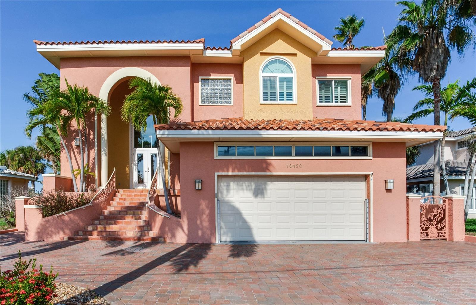 PANORAMIC WATER VIEWS STUNNING RESORT-STYLE POOL AND A SHORT WALK TO THE BEACH define this exceptional Mediterranean-style waterfront estate—an extraordinary opportunity to live the coastal lifestyle you’ve been dreaming of. Custom Built in 2000, this 4-bedroom, 3-full and 2-half bath luxury residence is nestled in the heart of Redington Beach, featuring block construction on all levels, impact windows throughout, accordion
hurricane shutters for sliding doors, and elevated living; the house has never flooded. The top floor showcases a breathtaking great room with soaring ceilings, luxury vinyl plank flooring, fireplace, and walls of picture windows capturing panoramic views of the bay and Intracoastal Waterway. A gourmet kitchen with custom wood cabinetry, induction cooktop, granite countertops, and spacious
dining area creates the perfect setting for upscale entertaining. A covered balcony extends the living space outdoors, framing endless open-water vistas. The grand primary suite on this level includes 2 spacious walk-in closets, a spa-style bathroom with jetted tub and walk-in shower. There is an additional bedroom and full bath with a jetted tub, laundry room, and an additional top floor half bath. Designed with
versatility in mind, the second floor has a spacious family room with a complete 7.2 Home Theater System, full kitchen, second primary bedroom, bunk room/bedroom,full bath with walk-in shower, and a half bath. There is a covered balcony, with stairway access to the pool. Whether used as an entertainment hub for the family, guest retreat, or separate living suite, the space enhances the home’s livability while
preserving privacy for everyone. The ground floor is a car collector’s dream, featuring high volume ceilings, 3 automotive lifts, compressor, and parking for up to seven vehicles with ease. High-volume ceilings create exceptional functionality for storage, maintenance, and display. Off the garage, a massive, fully enclosed storage area provides unparalleled space for storing recreational equipment, seasonal décor, tools, or anything else needed for waterfront living. The garage and storage areas are protected by a Garrison Hammerhead Flood Control System. There is an additional laundry area for guests. An elevator services all levels, ensuring effortless access throughout the estate. There is also a natural gas home generator, which powers the entire estate in the event of a power outage. Step outside to your private backyard oasis, rivaling the finest five-star resorts. Tropical landscaping surrounds the saltwater pool and spa, with Heat/Chiller heat pump, with water
features, and newer seawall. The 50-foot-deep water dock, with 3 boat lifts, makes boating a breeze. Experience true luxury waterfront living—where every day feels like a retreat.