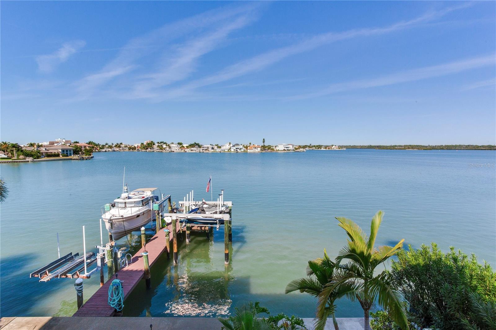 PANORAMIC WATER VIEWS STUNNING RESORT-STYLE POOL AND A SHORT WALK TO THE BEACH define this exceptional Mediterranean-style waterfront estate—an extraordinary opportunity to live the coastal lifestyle you’ve been dreaming of. Custom Built in 2000, this 4-bedroom, 3-full and 2-half bath luxury residence is nestled in the heart of Redington Beach, featuring block construction on all levels, impact windows throughout, accordion
hurricane shutters for sliding doors, and elevated living; the house has never flooded. The top floor showcases a breathtaking great room with soaring ceilings, luxury vinyl plank flooring, fireplace, and walls of picture windows capturing panoramic views of the bay and Intracoastal Waterway. A gourmet kitchen with custom wood cabinetry, induction cooktop, granite countertops, and spacious
dining area creates the perfect setting for upscale entertaining. A covered balcony extends the living space outdoors, framing endless open-water vistas. The grand primary suite on this level includes 2 spacious walk-in closets, a spa-style bathroom with jetted tub and walk-in shower. There is an additional bedroom and full bath with a jetted tub, laundry room, and an additional top floor half bath. Designed with
versatility in mind, the second floor has a spacious family room with a complete 7.2 Home Theater System, full kitchen, second primary bedroom, bunk room/bedroom,full bath with walk-in shower, and a half bath. There is a covered balcony, with stairway access to the pool. Whether used as an entertainment hub for the family, guest retreat, or separate living suite, the space enhances the home’s livability while
preserving privacy for everyone. The ground floor is a car collector’s dream, featuring high volume ceilings, 3 automotive lifts, compressor, and parking for up to seven vehicles with ease. High-volume ceilings create exceptional functionality for storage, maintenance, and display. Off the garage, a massive, fully enclosed storage area provides unparalleled space for storing recreational equipment, seasonal décor, tools, or anything else needed for waterfront living. The garage and storage areas are protected by a Garrison Hammerhead Flood Control System. There is an additional laundry area for guests. An elevator services all levels, ensuring effortless access throughout the estate. There is also a natural gas home generator, which powers the entire estate in the event of a power outage. Step outside to your private backyard oasis, rivaling the finest five-star resorts. Tropical landscaping surrounds the saltwater pool and spa, with Heat/Chiller heat pump, with water
features, and newer seawall. The 50-foot-deep water dock, with 3 boat lifts, makes boating a breeze. Experience true luxury waterfront living—where every day feels like a retreat.