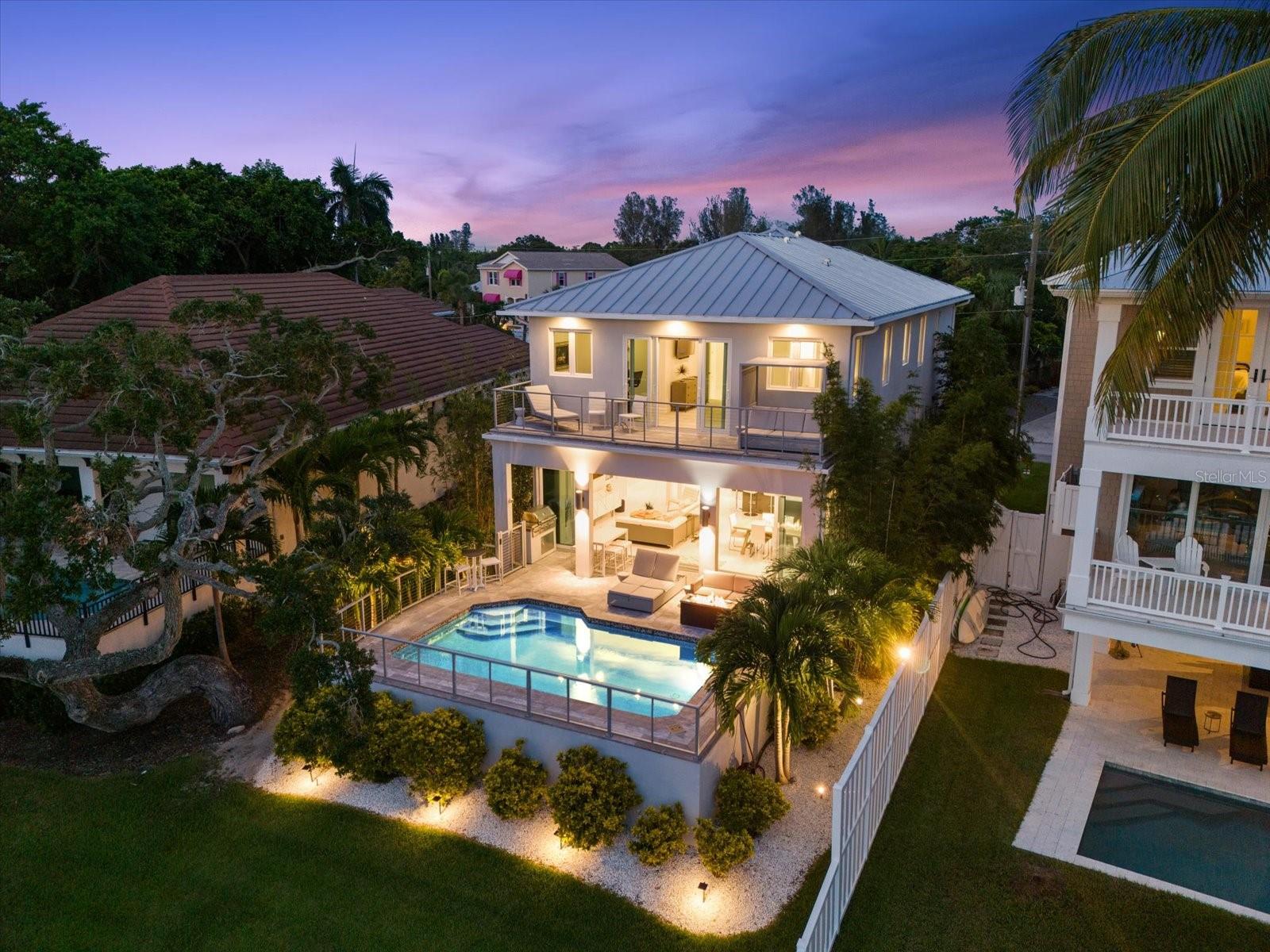 Come live the good life on Siesta Key in this spectacular Grand Canal- front home with water views, boat dock, bay access & gorgeous salt pool with travertine decking & custom summer kitchen. Casual elegance is exuded in every room of this 3 BR, 3.5 BA home, from the 1200 sq. ft. sprawling European style open kitchen to the full wall of glass sliders opening to the expansive outdoor living space.  The main level of this 2019 custom home boasts an oversized entry foyer, a light and bright open kitchen flowing into the living area, sliders to the open pool with cable wire railing and built-in summer kitchen.  The second level of the home features an extraordinary primary suite with an outdoor sitting area and covered balcony with views of the pool and Grand Canal.  Enjoy a large soaking tub and spacious shower in the primary bath and an expansive primary closet.  Two additional en suite guest bedrooms and a laundry room round out the second floor living areas.  NO HOA Fees is an added plus!  Highlights of this home include hurricane impact windows/doors, elevator with three stops- garage, main and top levels, Tesla charging station, automated custom European window treatments, central vacuum system, and new 10,000 lb. boat lift and dock (built to fit a 27' boat),  oversized two car garage, balconies at front and back of the home, etc.  Just minutes from the intracoastal waterway, Gulf of Mexico, and Siesta Key village!  Siesta Key is proud to provide the best coastal lifestyle possible - island living, breath-taking sunsets, boating and award winning beaches are at your doorstep!